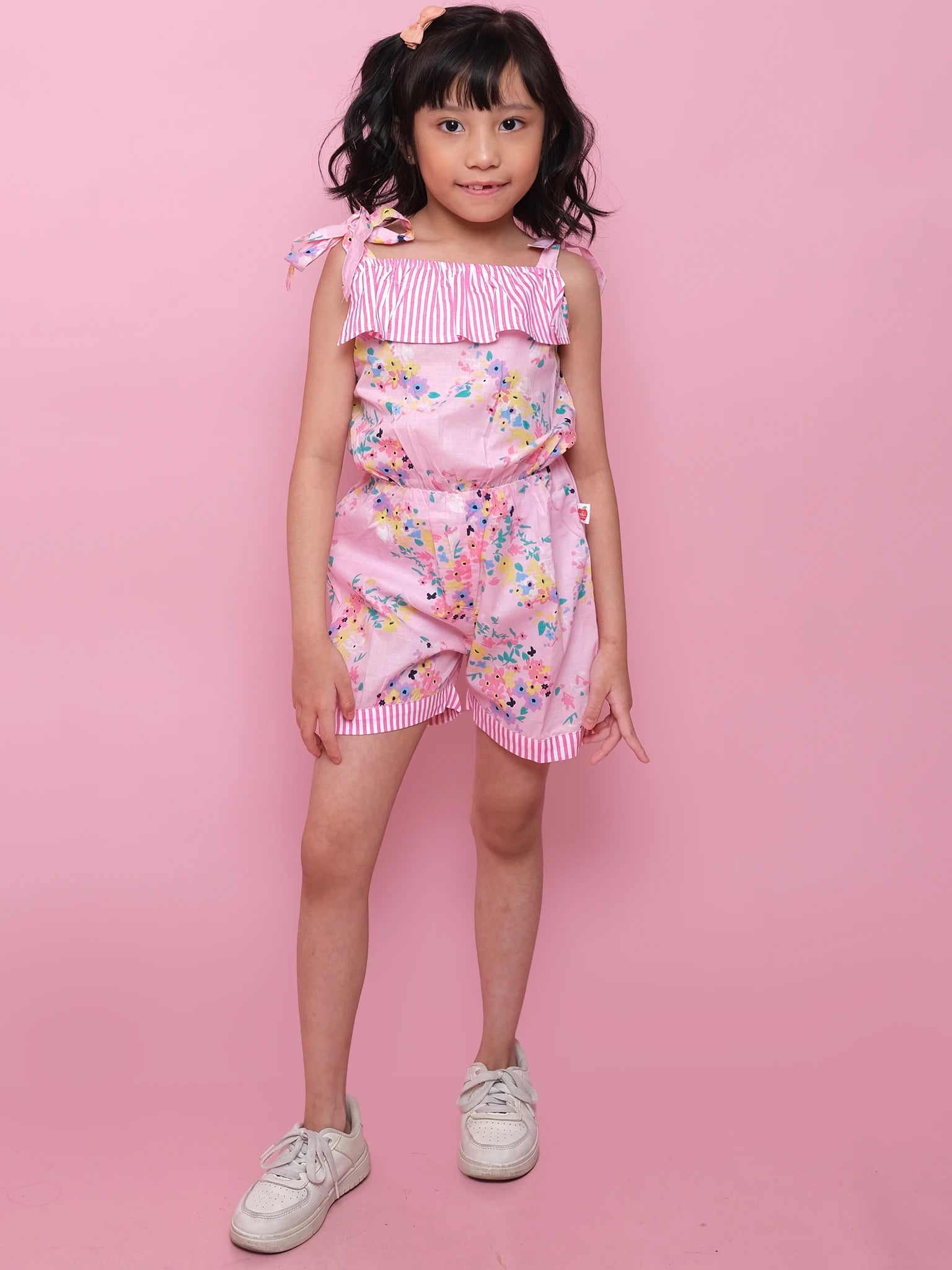 A girl in a Confetti Floral Josie Playsuit and summer hat, dressed in lightweight cotton.