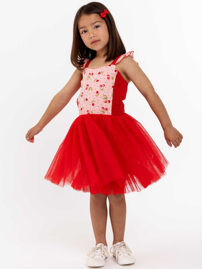A little girl in a Retro Cherry Cherry Ripe Belle Tutu Dress posing on a white background.