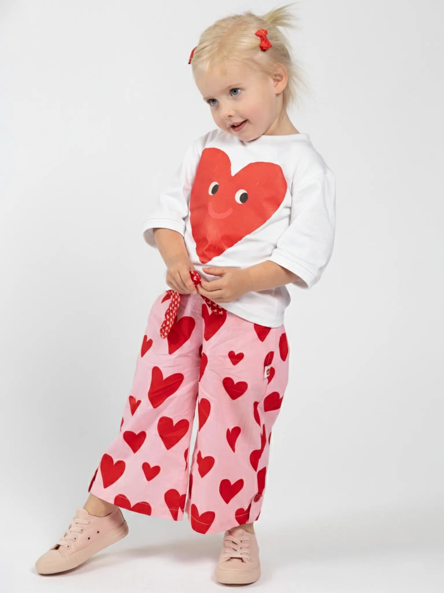 Girls wearing Oobi cotton skirts and pants in bright prints, twirling and playing outdoors.