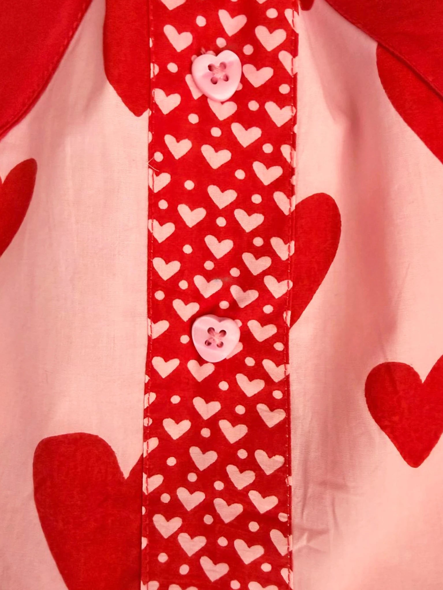 Close-up of the Big Hearts Big Heart Pocket Skirt, featuring a red and white heart pattern with pink heart-shaped buttons, crafted from hand-printed cotton.