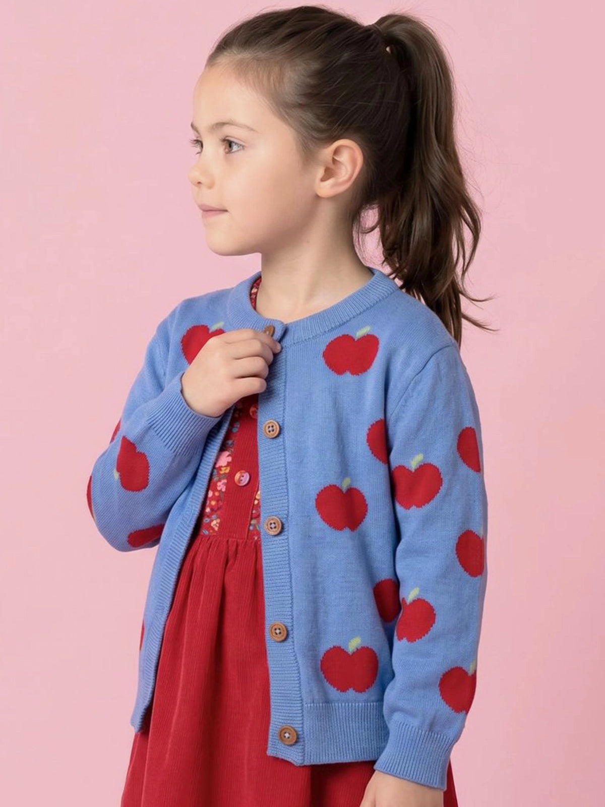 Girl in Blue Apple cardigan over a red dress