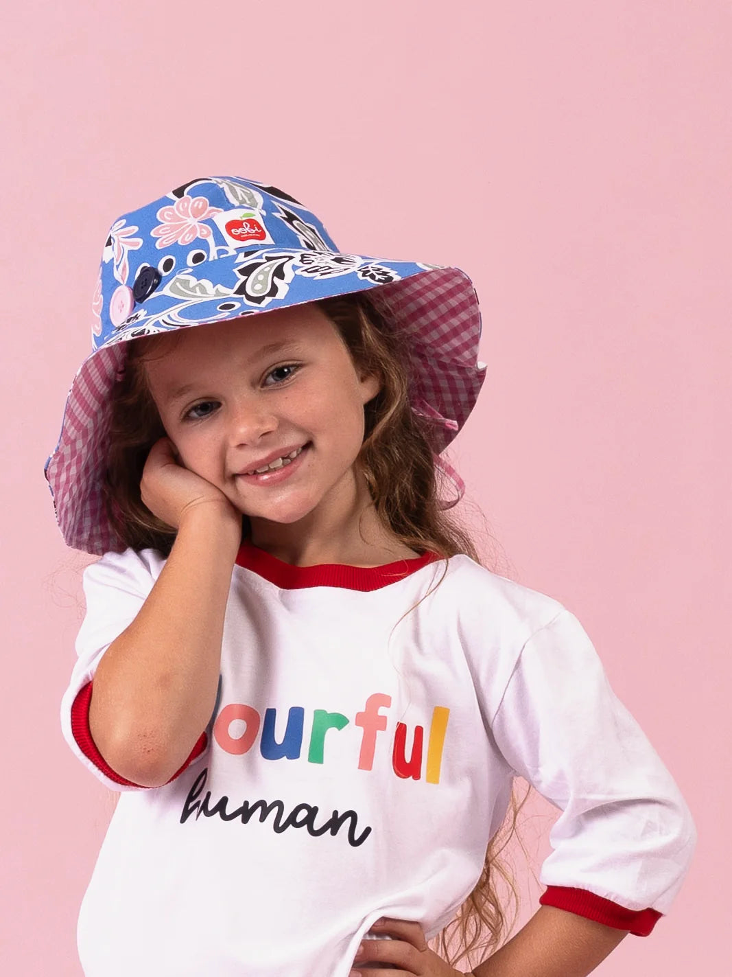 Girl smiling in the Blue/Pink Chloe ponytail hat, blue floral brim with pink gingham lining