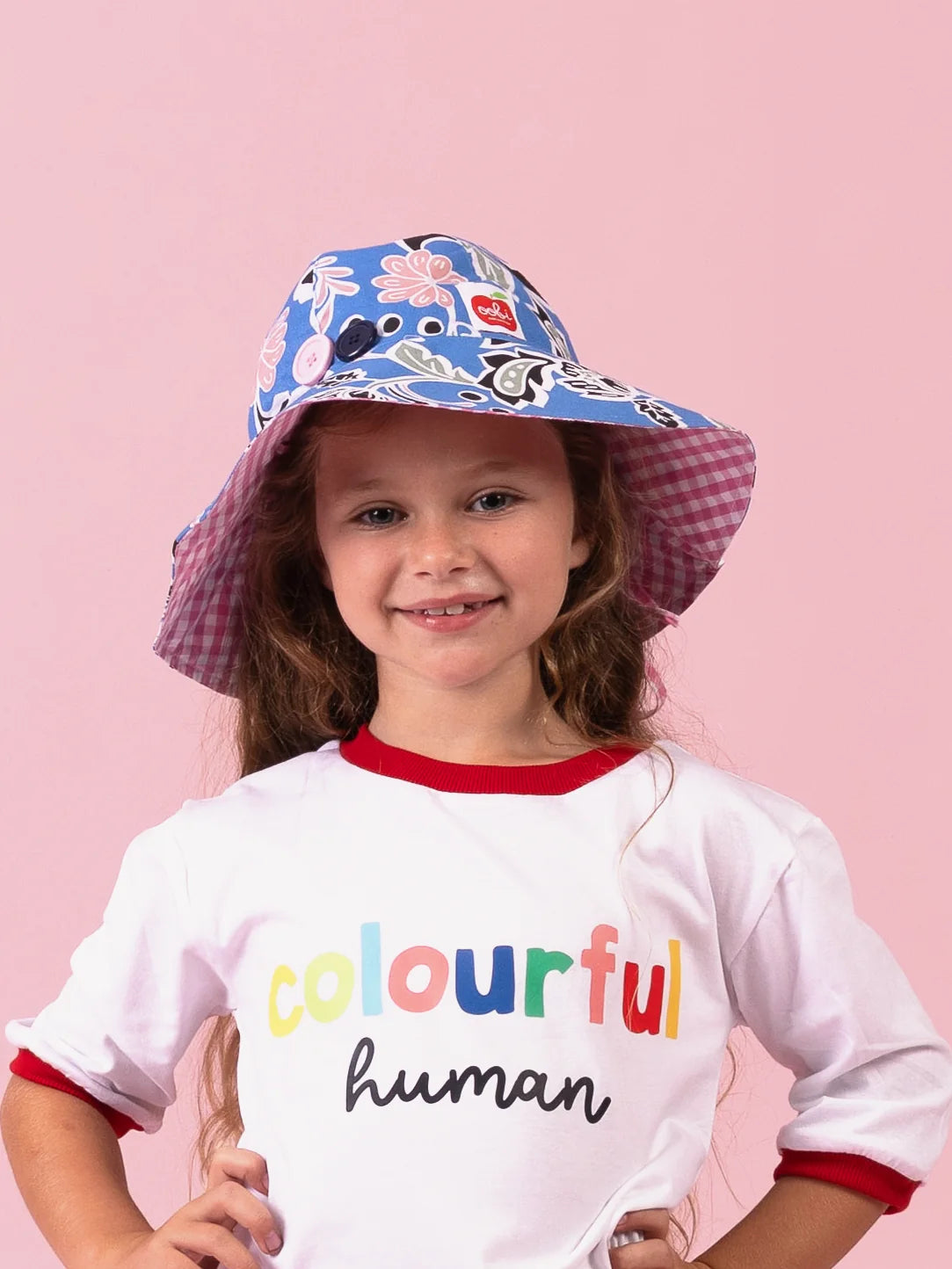 Girl smiling in the Blue/Pink Chloe ponytail hat, blue floral brim with pink gingham lining