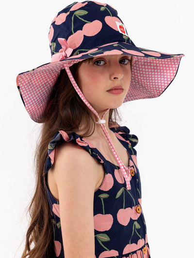 A young girl wearing a Navy Cherry Chloe Hat from the brand Navy Cherry.