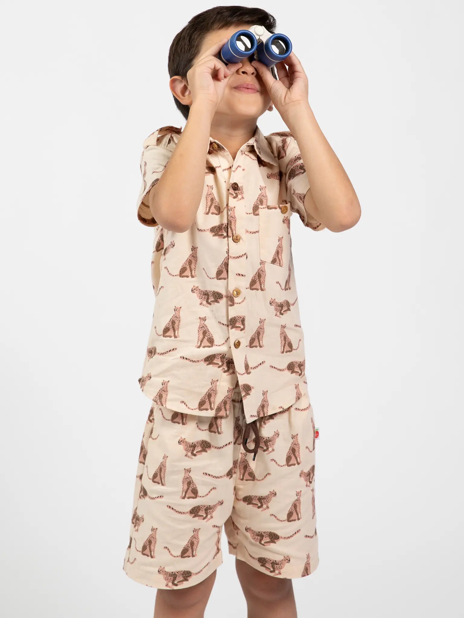 Child wearing a pajama set with cat print, holding binoculars on a white background