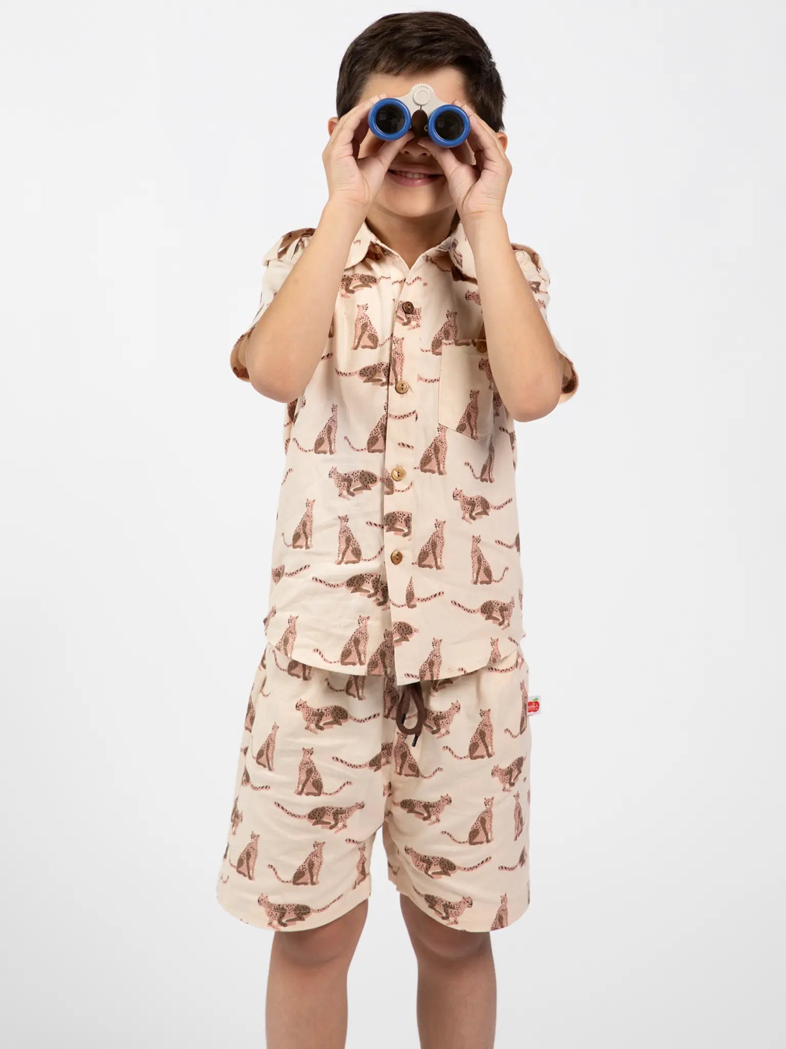 Child wearing a collared shirt and shorts set with leopard print holding binoculars on a white background