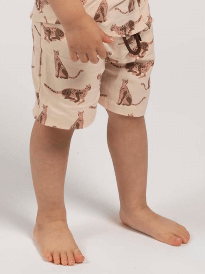 Child wearing shorts with a pattern of leopards on a plain background