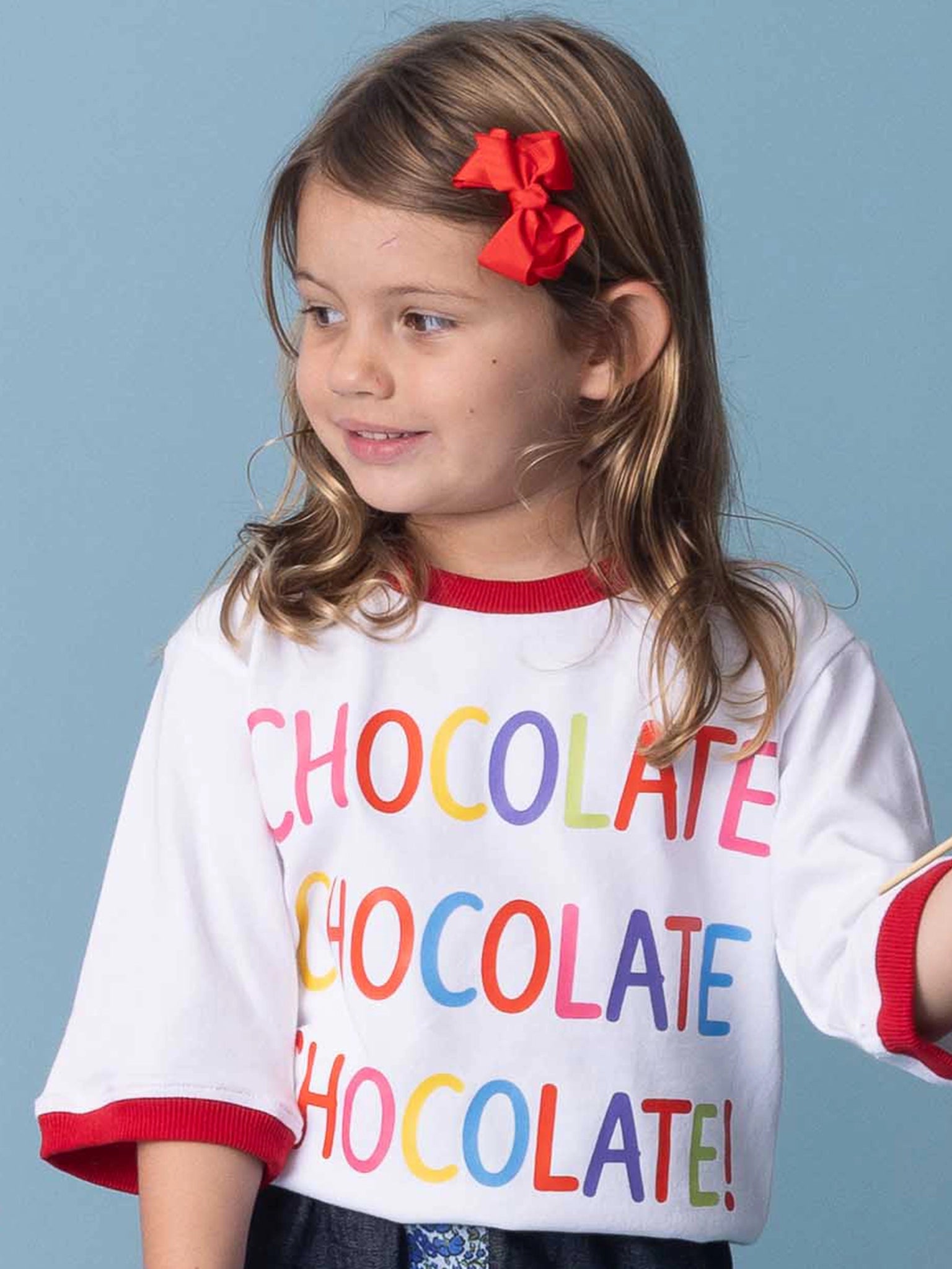 Child wearing a colorful 'CHOCOLATE' shirt against a blue background