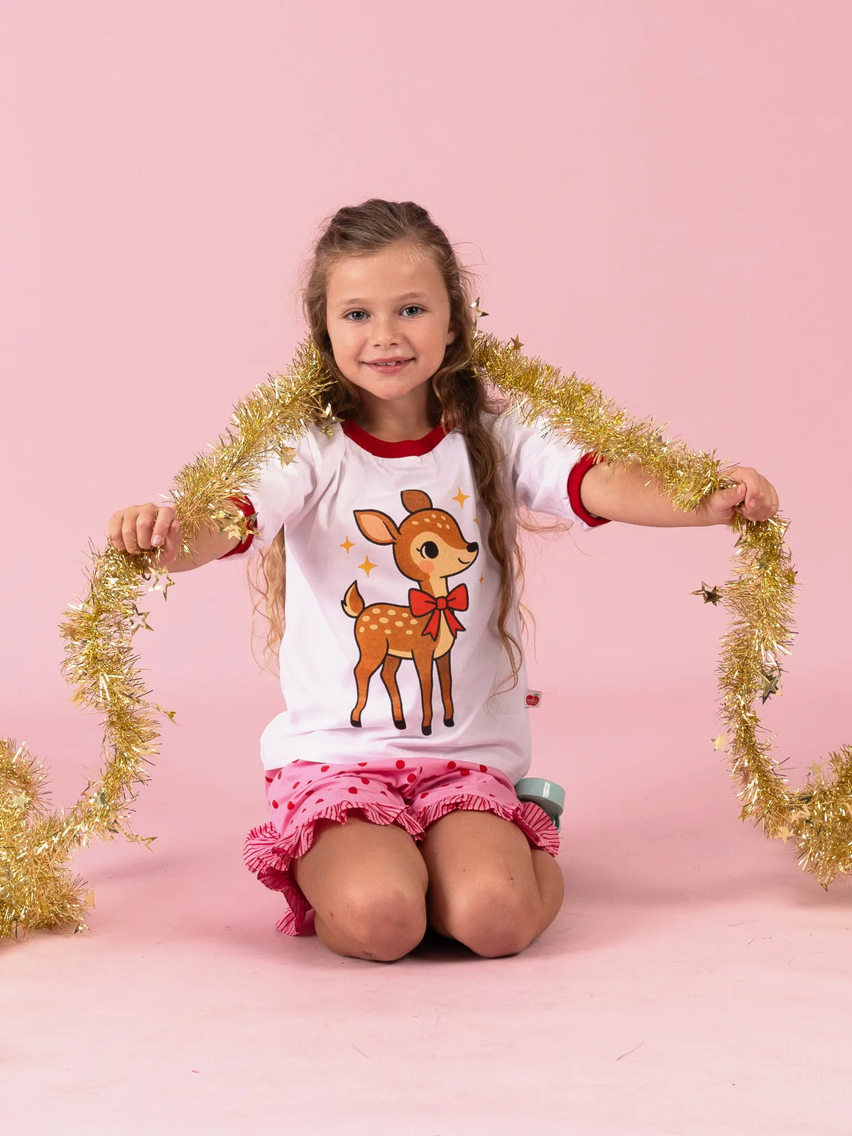 Girl stretching gold tinsel wide in the white Christmas Deer tee