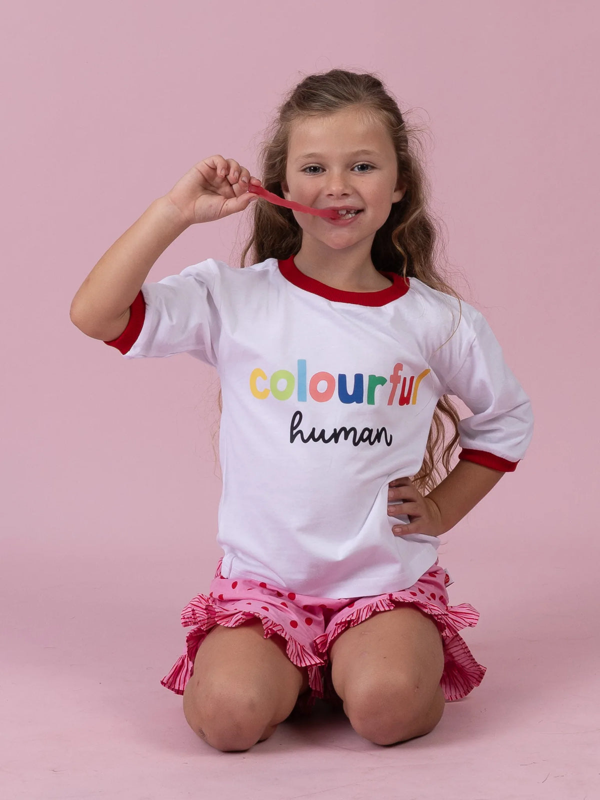 Smiling girl in the Colourful Human tee with rainbow lettering and red binding