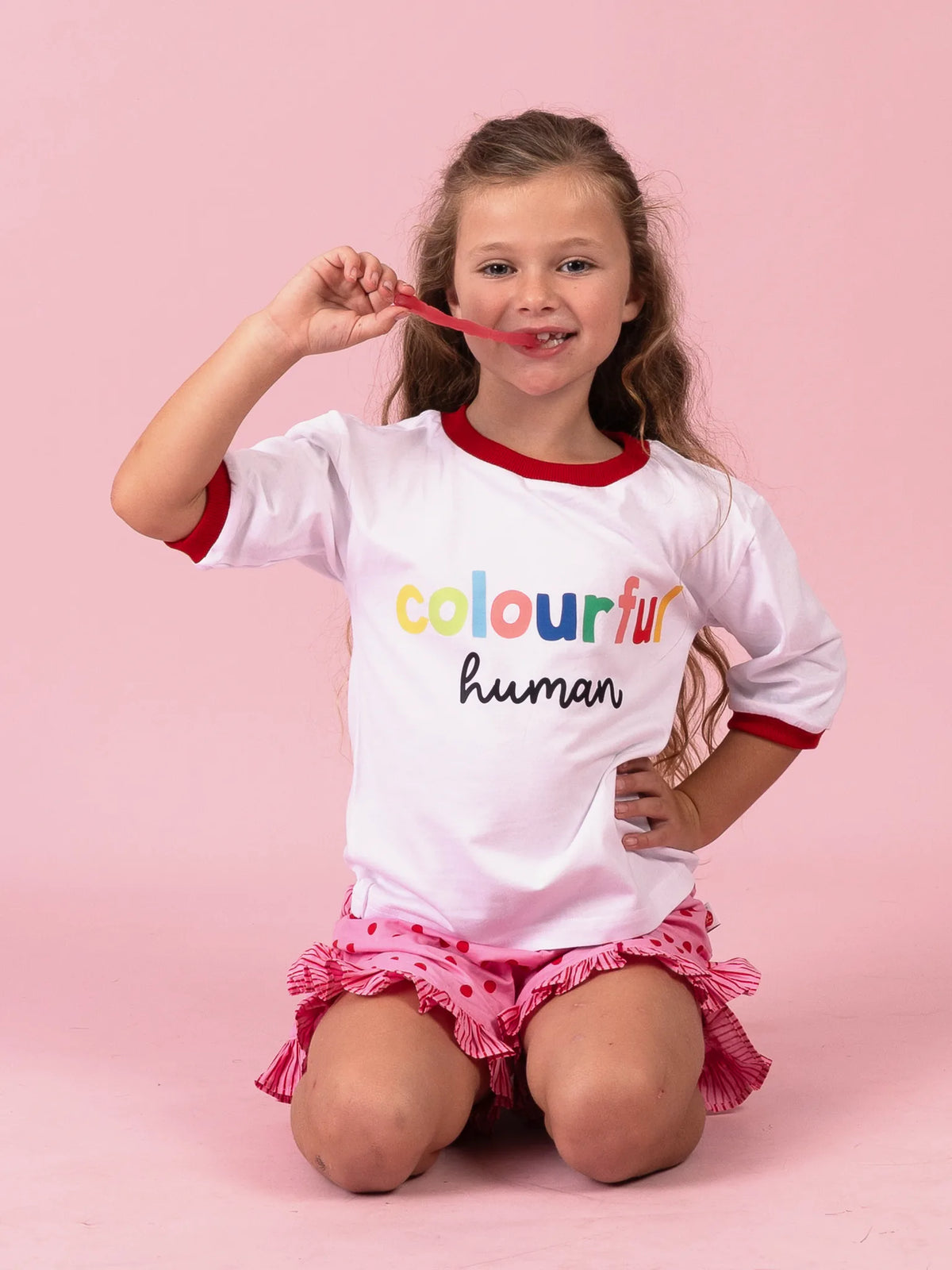 Smiling girl in the Colourful Human tee with rainbow lettering and red binding