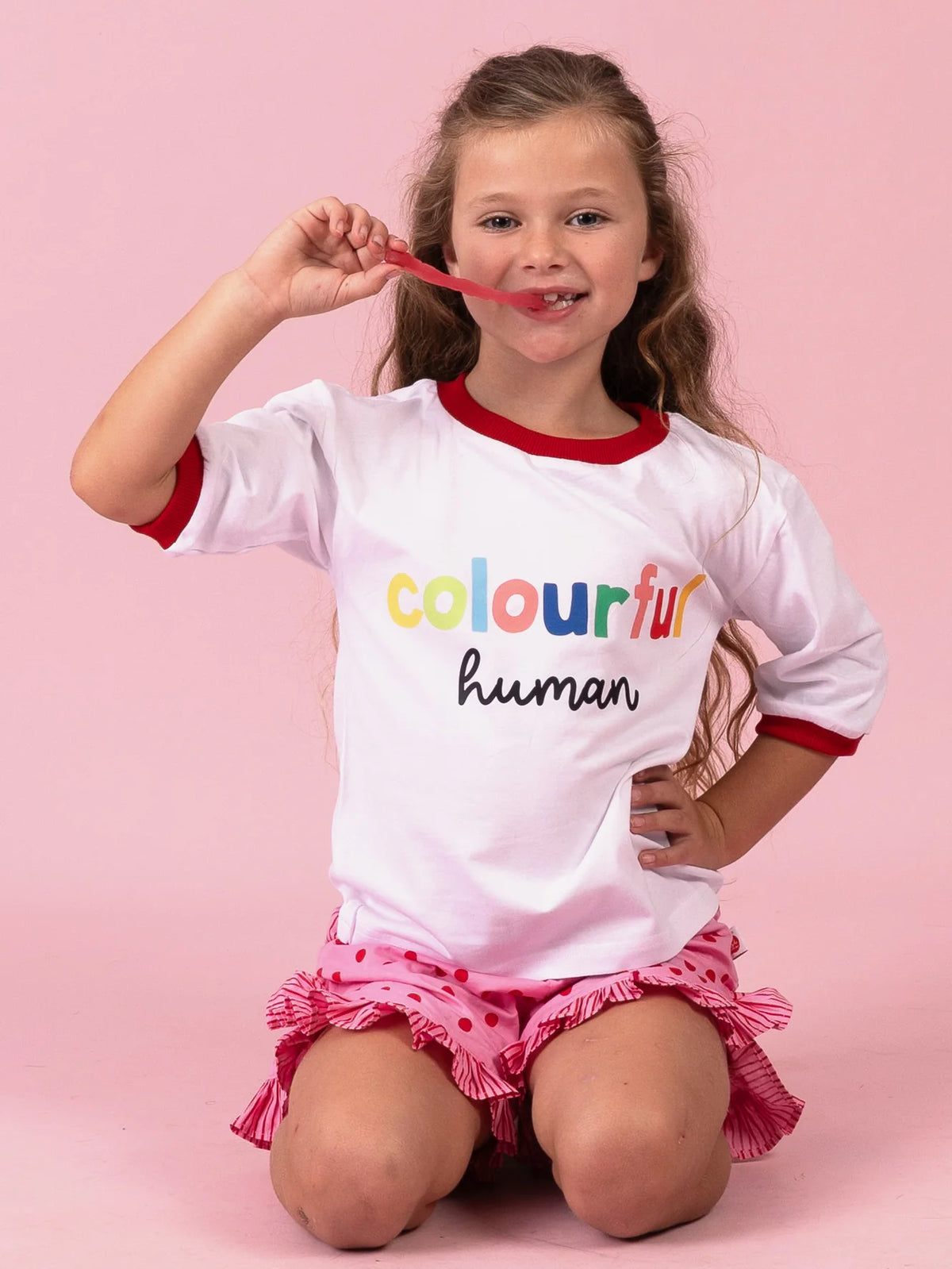 Smiling girl in the Colourful Human tee with rainbow lettering and red binding