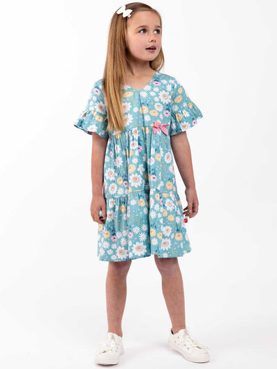 A little girl wearing the Elise Happy Daisies Dress from the brand Happy Daisies with flowers on it.