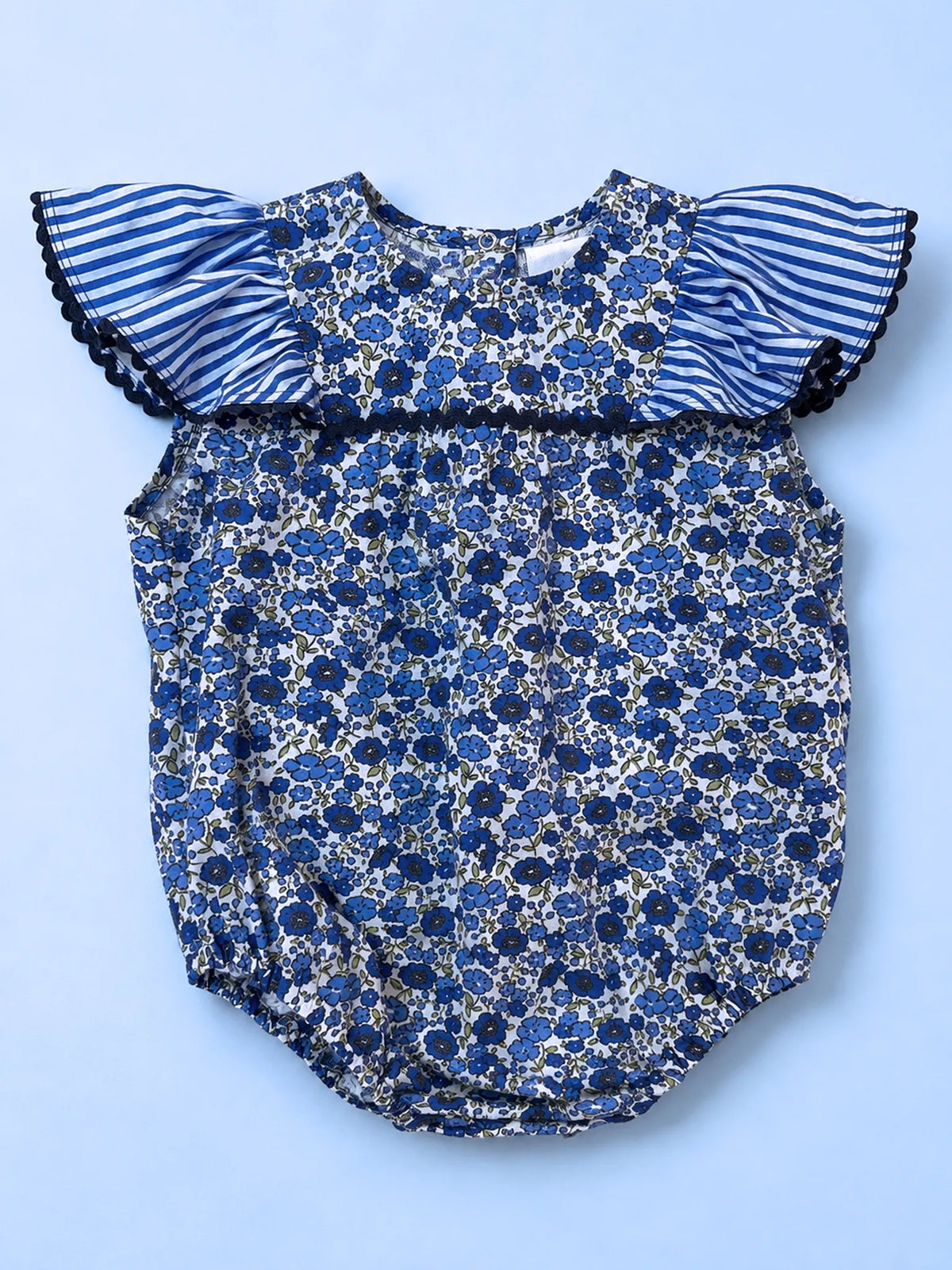 A baby romper with a blue and white floral print body and blue-and-white striped ruffle sleeves with black lace trim, laid flat on a light blue background.