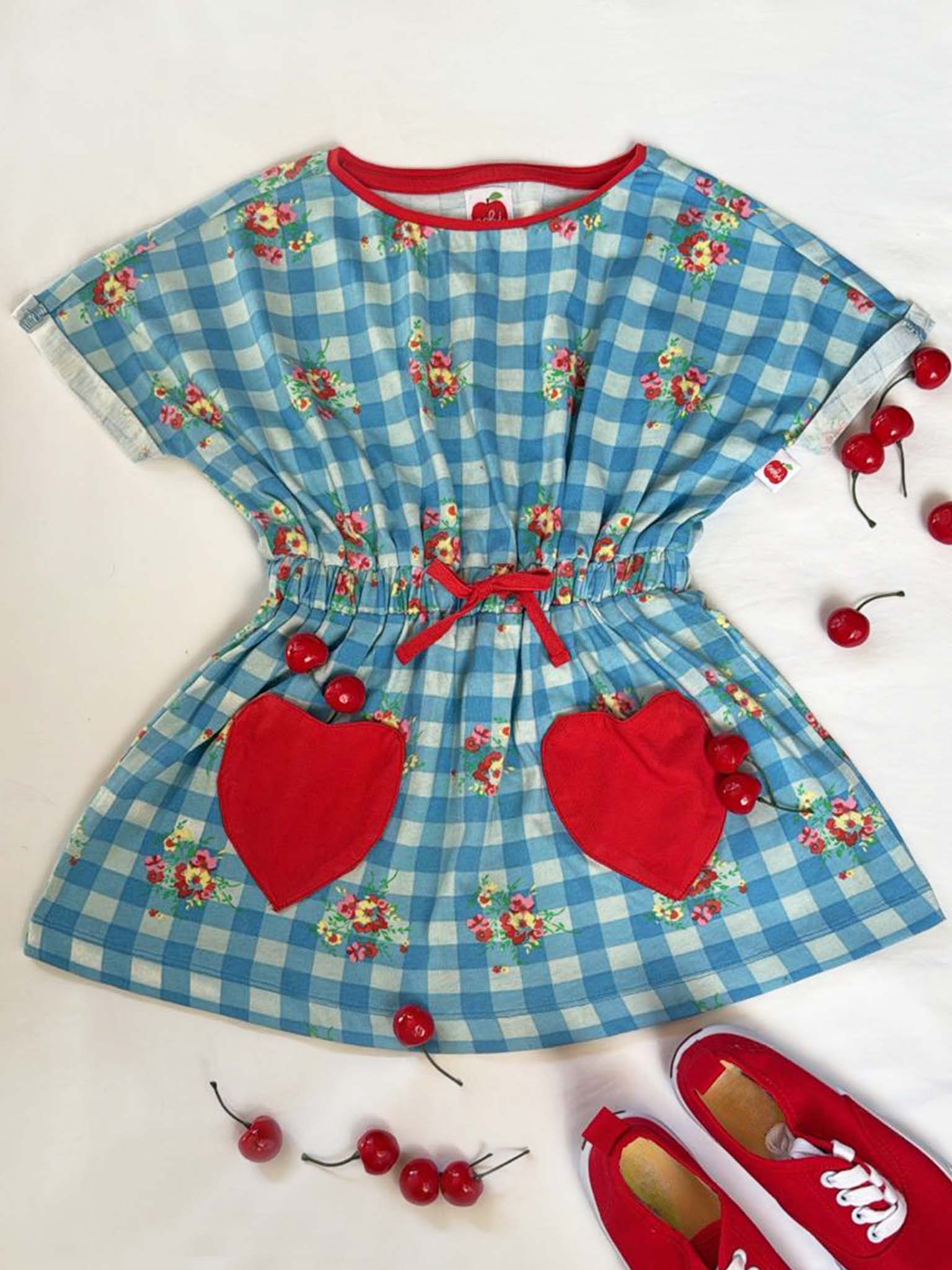 Children's dress with blue checkered pattern, red hearts, and cherry details on a white background