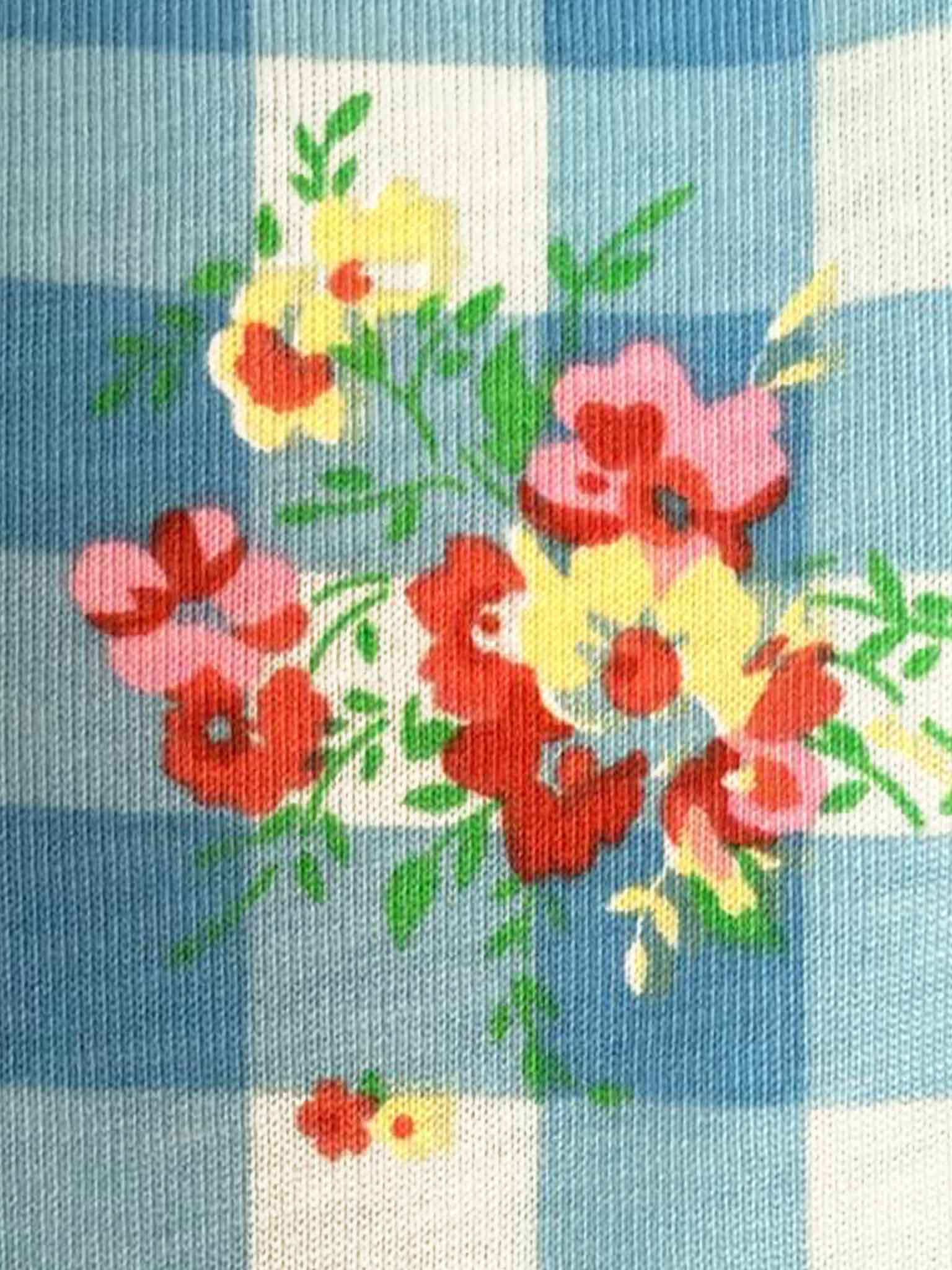 The Floral Gingham Ponytail Hat by Floral Gingham features red, yellow, and pink flowers with green leaves on a blue and white checkered background—perfect for kids or anyone wanting a fun floral look.