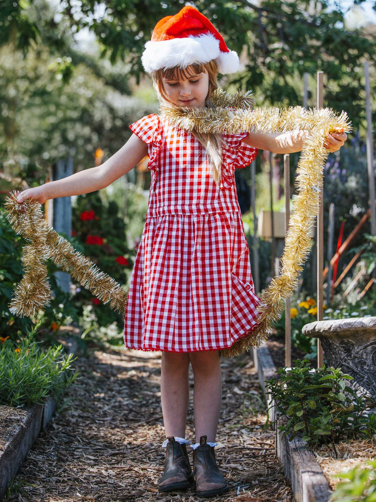 Girl and mum wearing Oobi Christmas dresses for family photos under the tree.