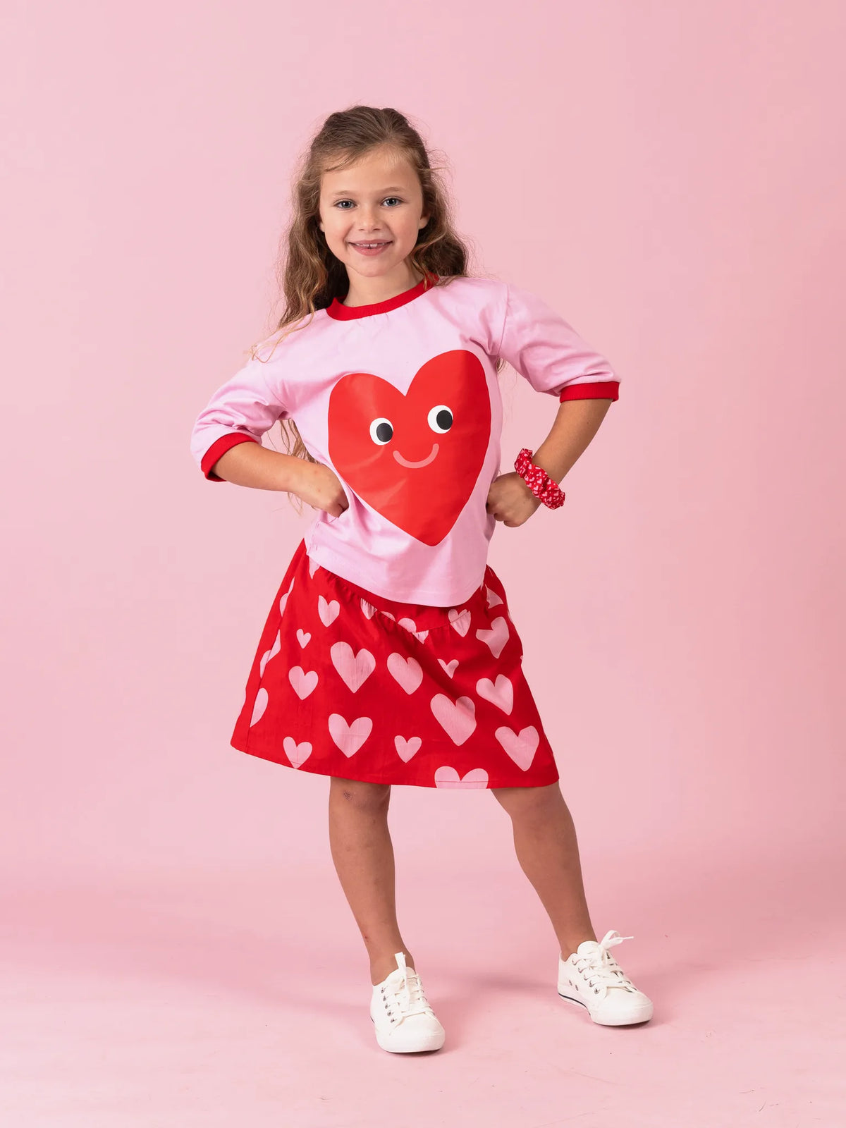 Smiling girl in the Happy Heart tee on pink with the Big Red Heart skirt