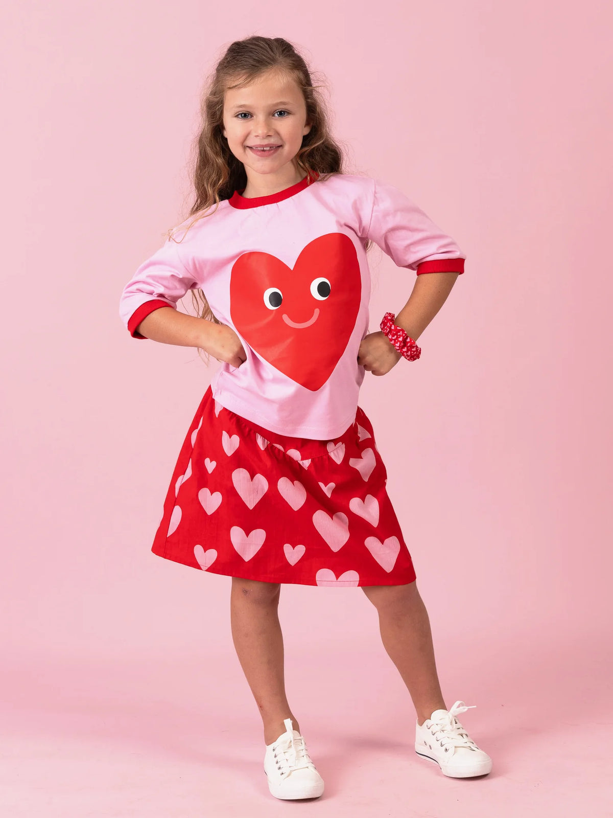 Smiling girl in the Happy Heart tee on pink with the Big Red Heart skirt