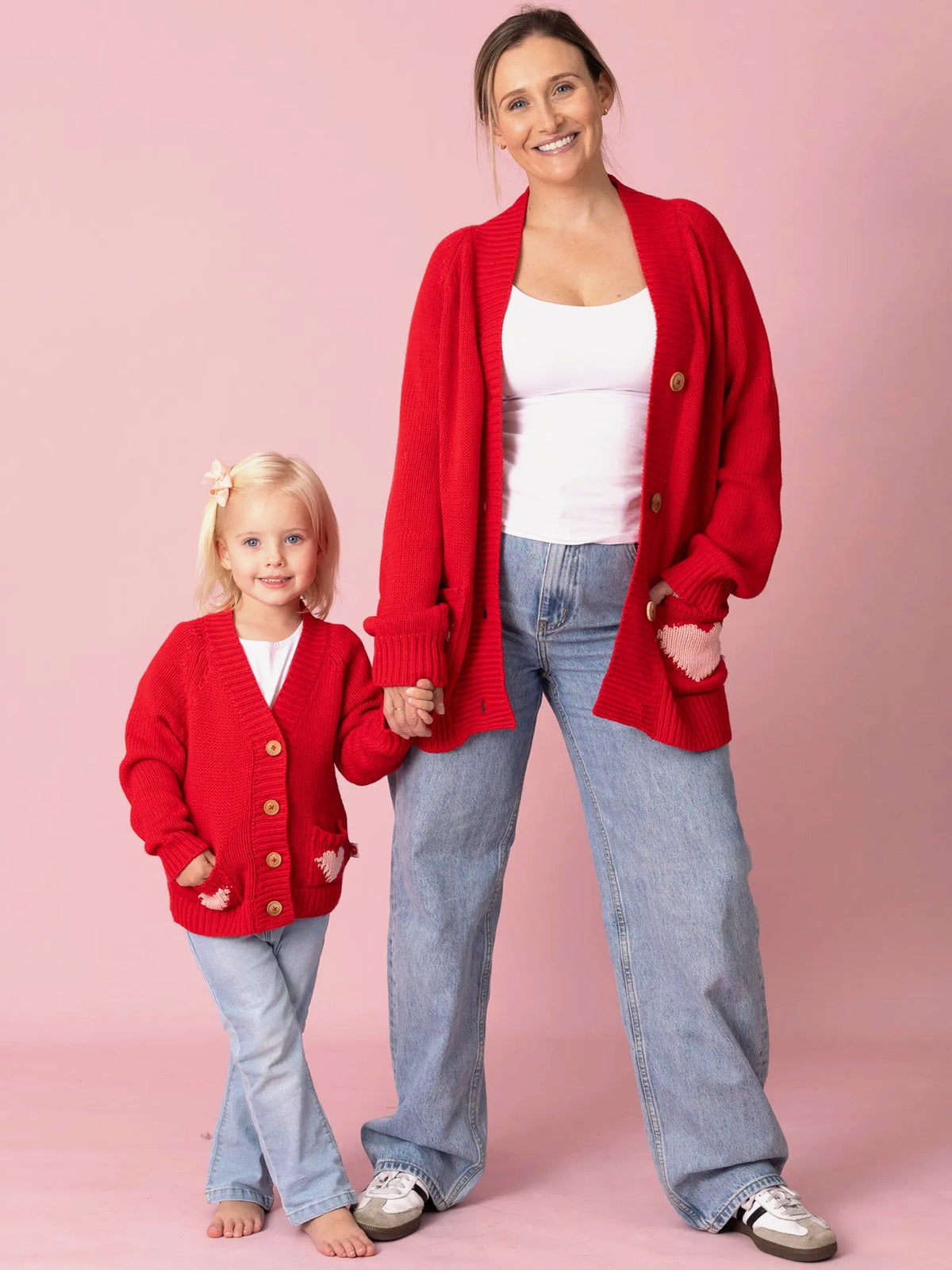 Woman and child wearing red cardigans against a pink background