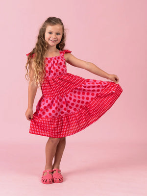 Girl showing the tiered skirt of the red and pink Jaipur Holiday dress