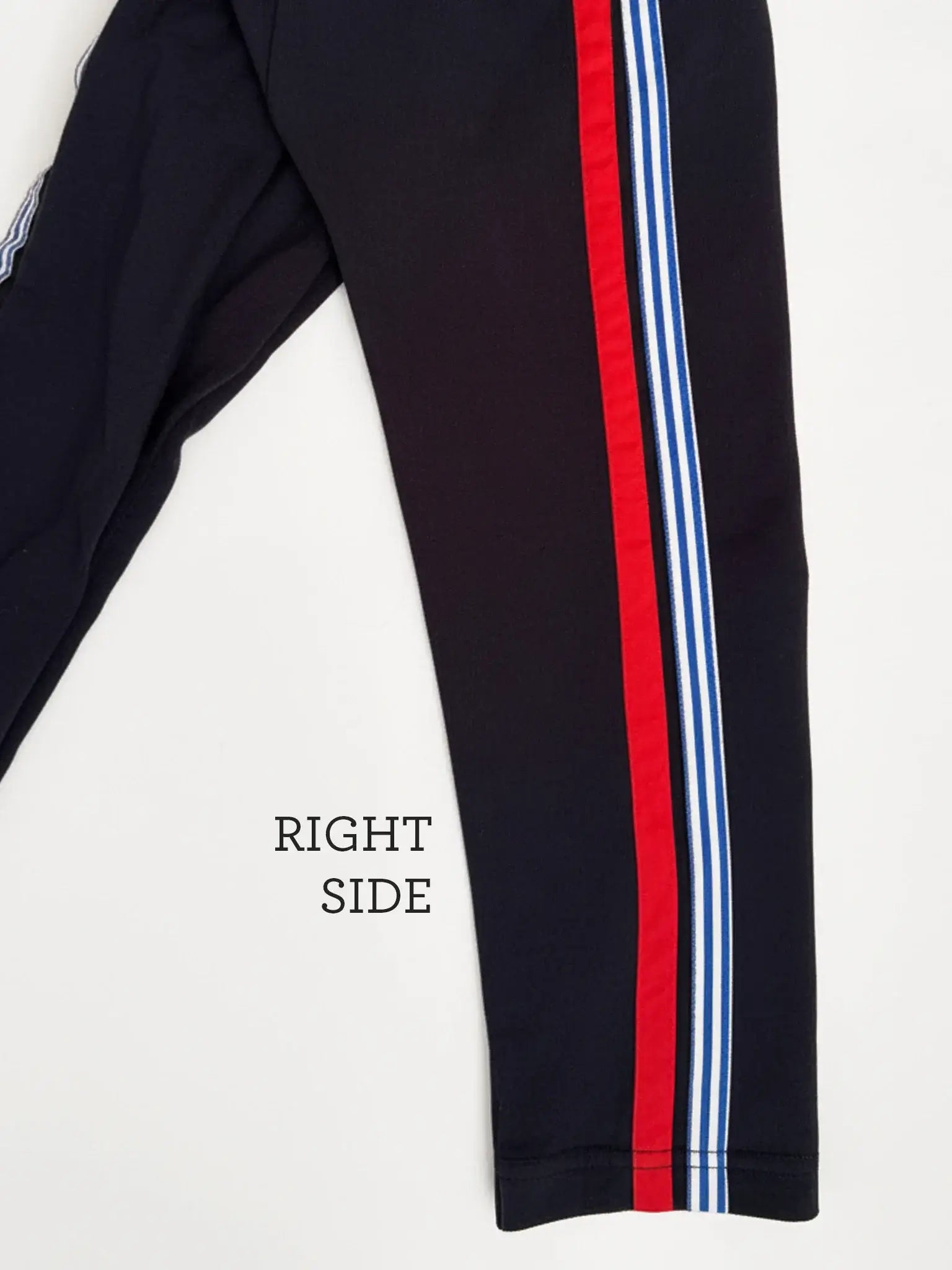 Essentials Navy Jersey 2 Stripe Pants feature bold red and white stripes down the right side—ideal for kids' sportswear. Shown on a white background.
