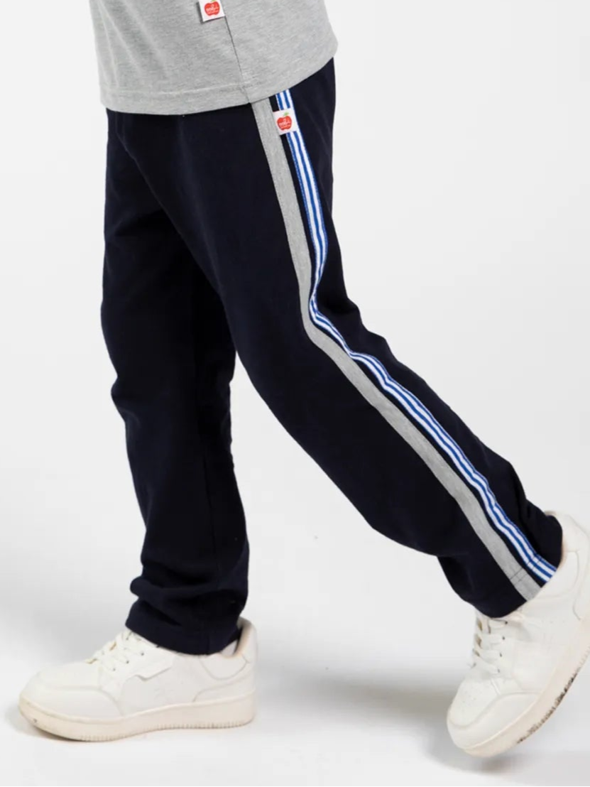 A person shown from the waist down wears Essentials Navy Jersey 2 Stripe Pants with white sneakers, set against a plain background.