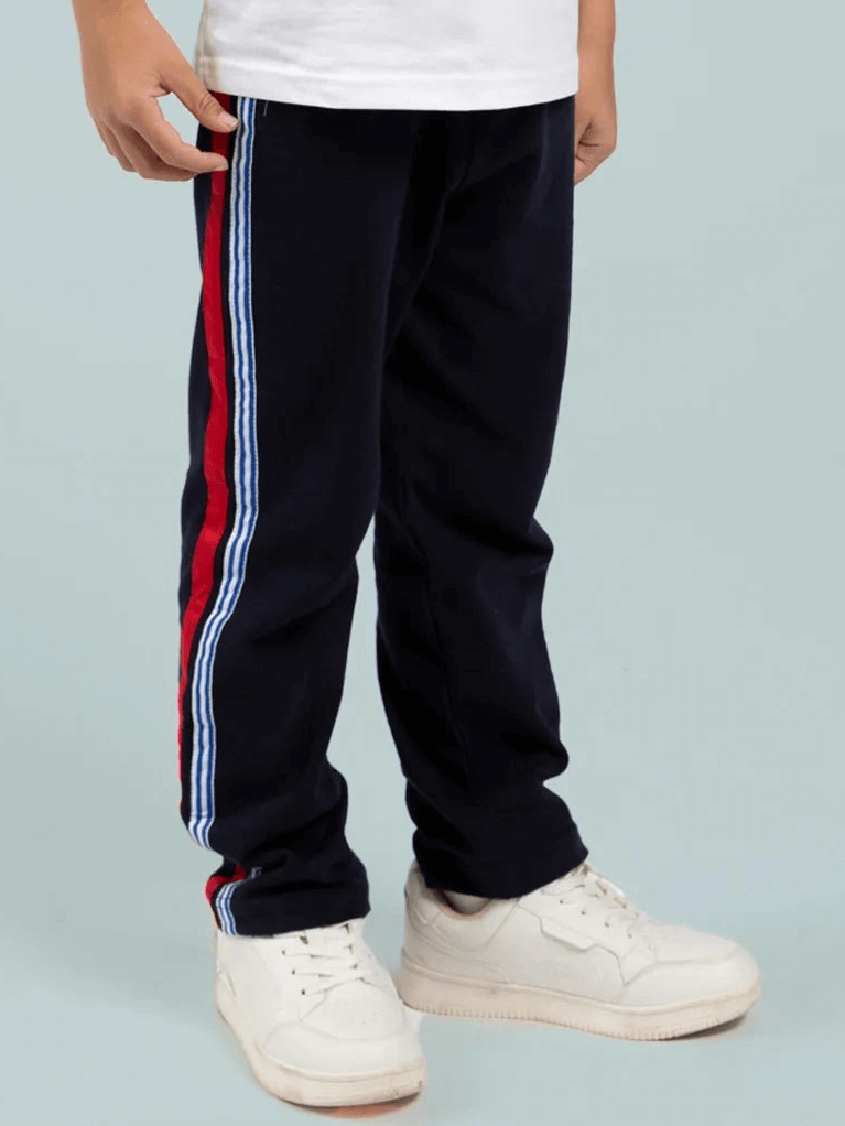 A person wearing Essentials Navy Jersey 2 Stripe Pants, a white t-shirt, and white sneakers stands against a plain light background.