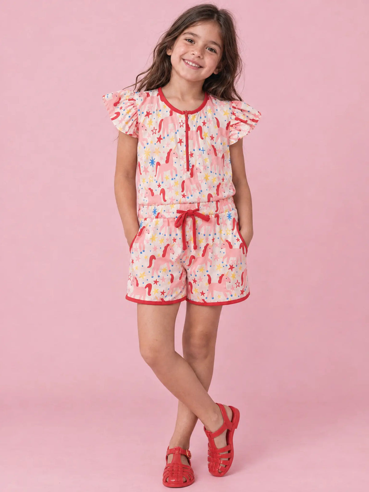 Girl in Magical Unicorn jersey playsuit with flutter sleeves and red drawstring
