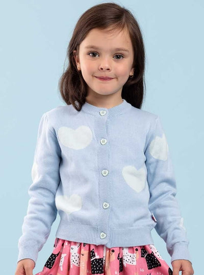 A little girl wearing a Maxine Starlight Hearts Cotton Cardigan by Knitwear with heart-shaped buttons.