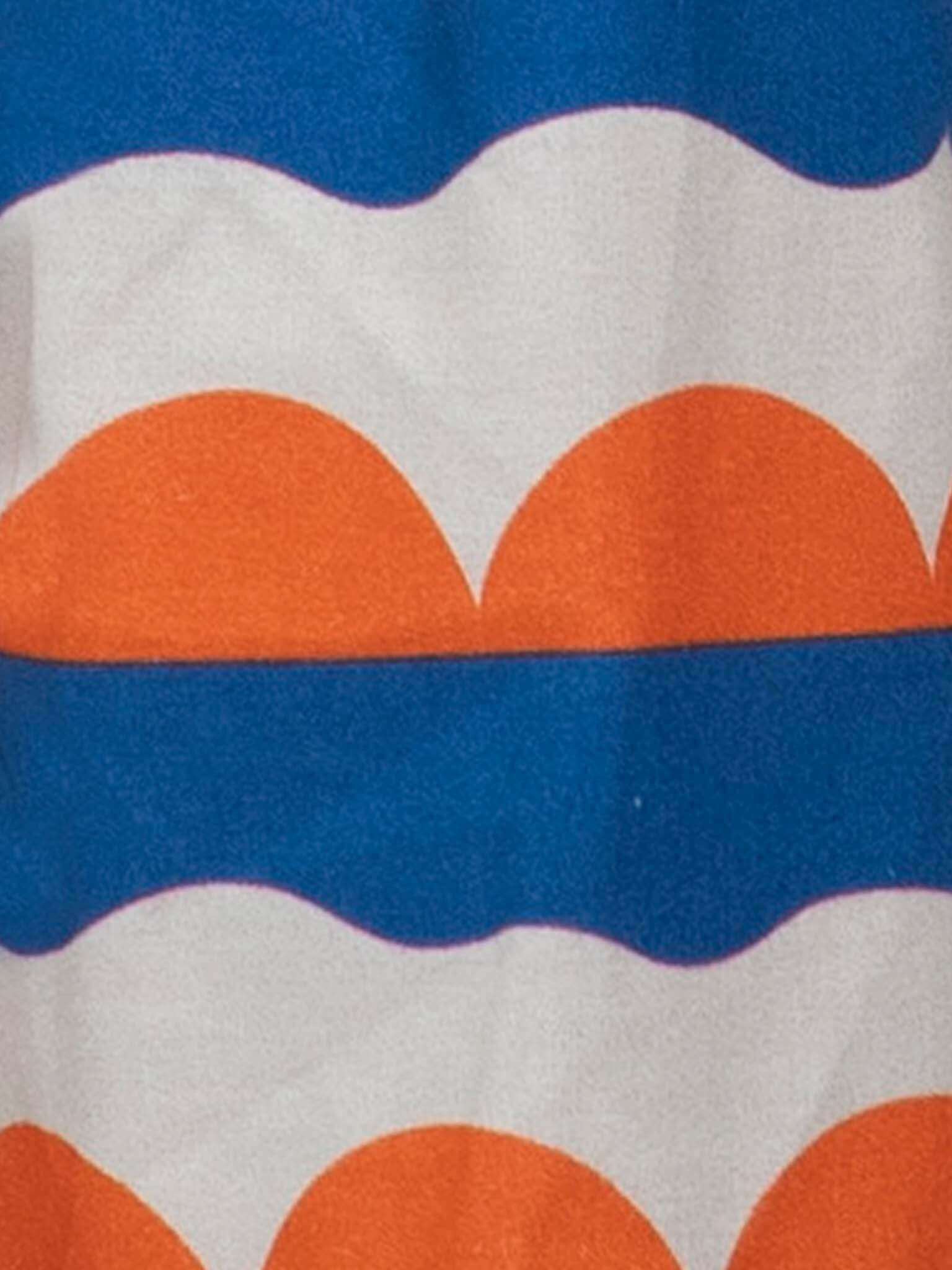 A close-up of Nautical’s Nautical Holiday Dress shows 100% cotton fabric with orange semi-circles, white waves, and blue stripes—ideal for an ethically crafted, nautical-inspired look.
