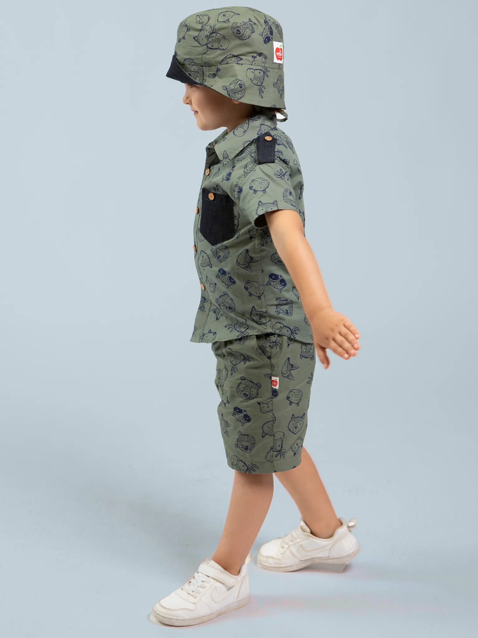 Child wearing a green safari outfit with a hat on a light gray background