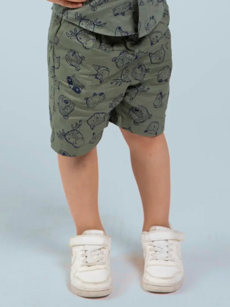 Child wearing green shorts with a pattern and white sneakers on a light blue background