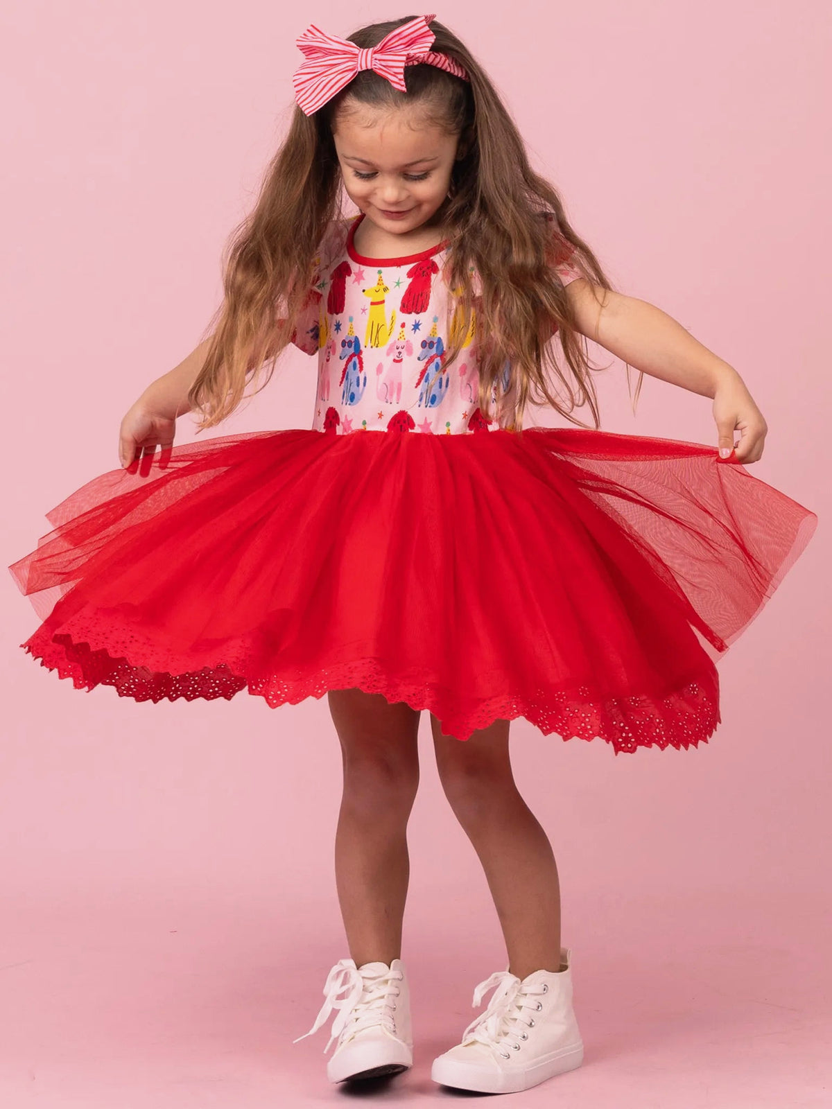 Girl spreading the red tulle skirt of her Party Pooches tutu dress