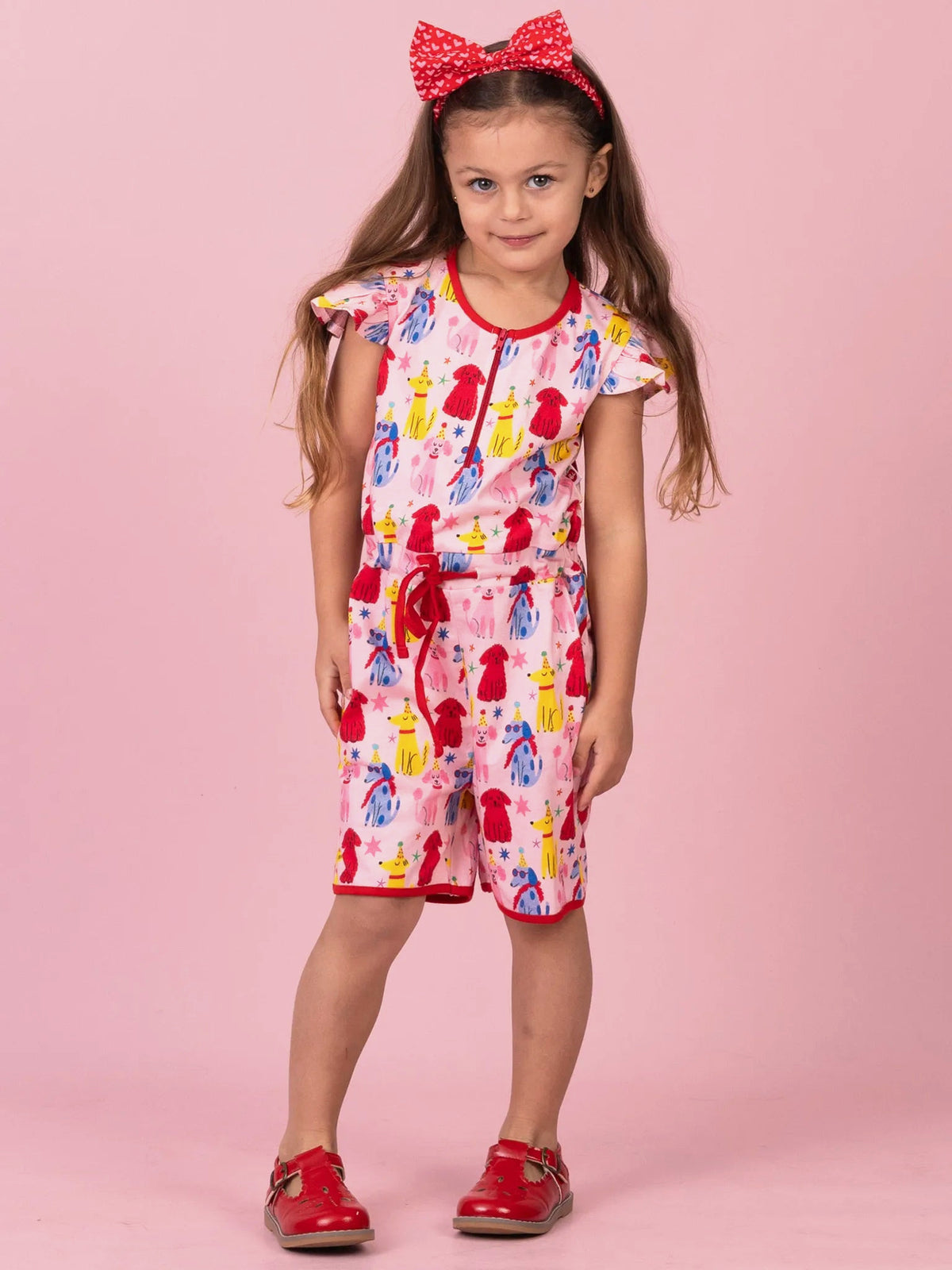 Girl in Party Pooches jersey playsuit with a red bow headband