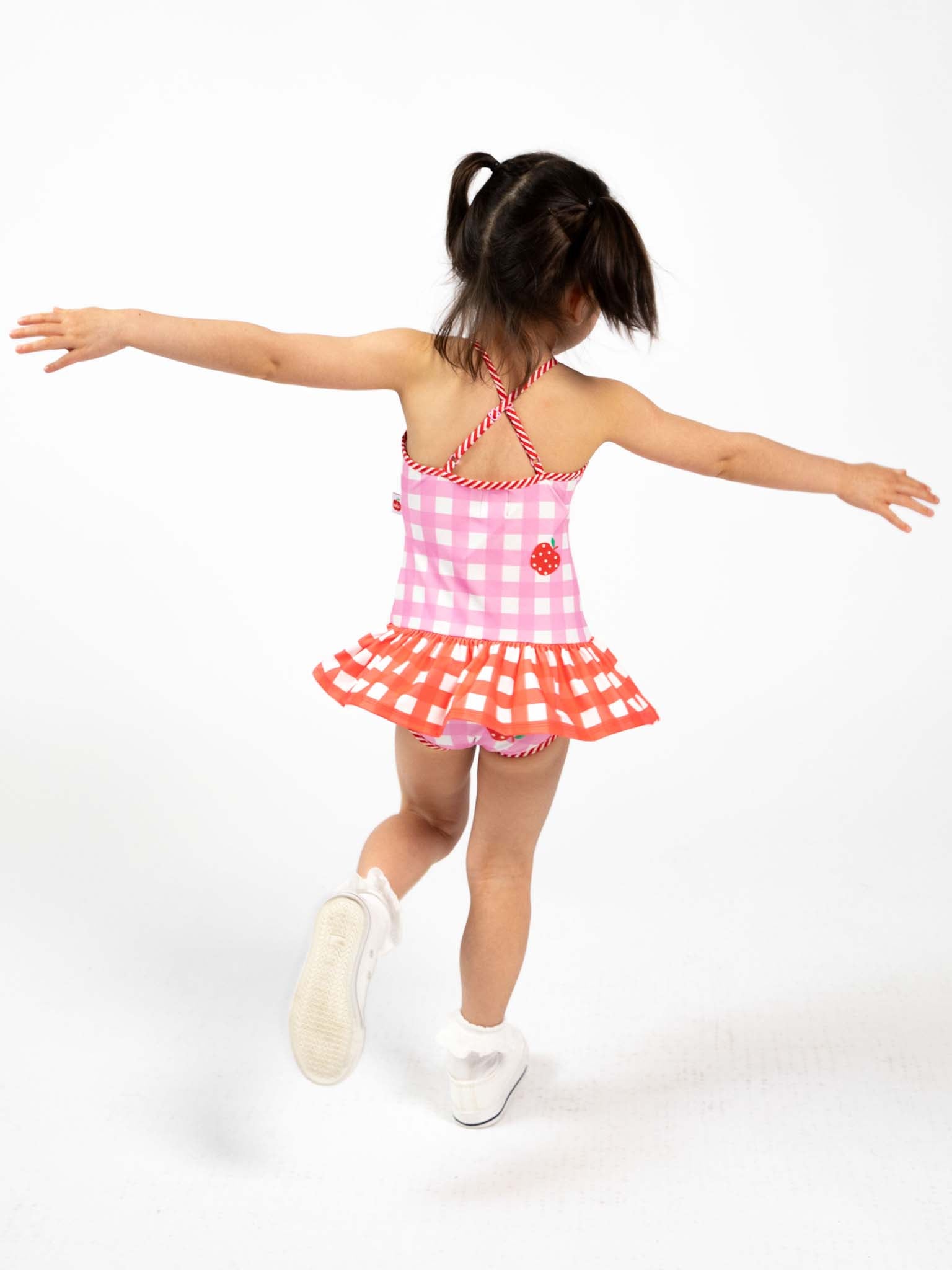 Child wearing a pink and white gingham checkered swimsuit