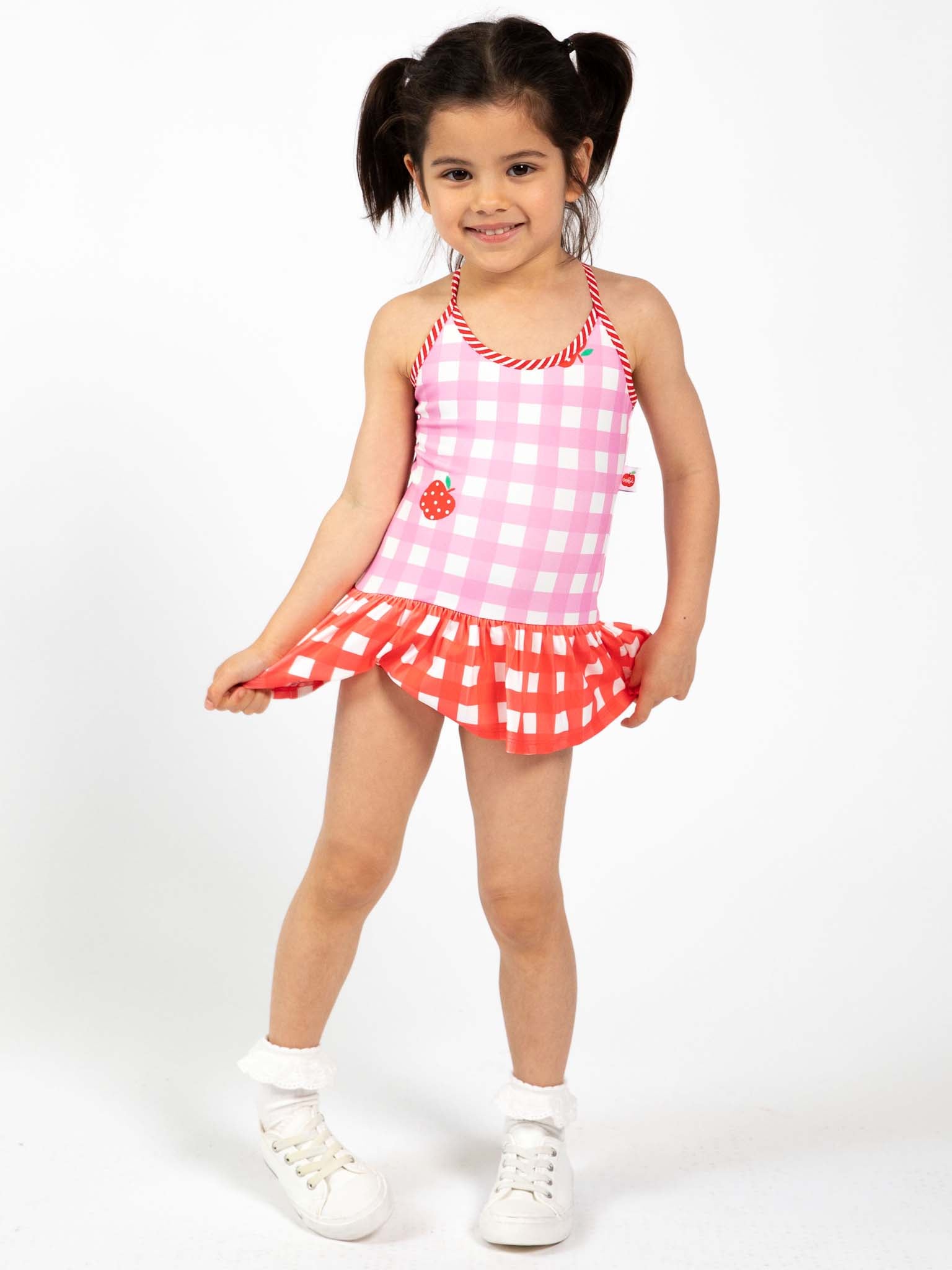 Child wearing a pink and white gingham checkered swimsuit