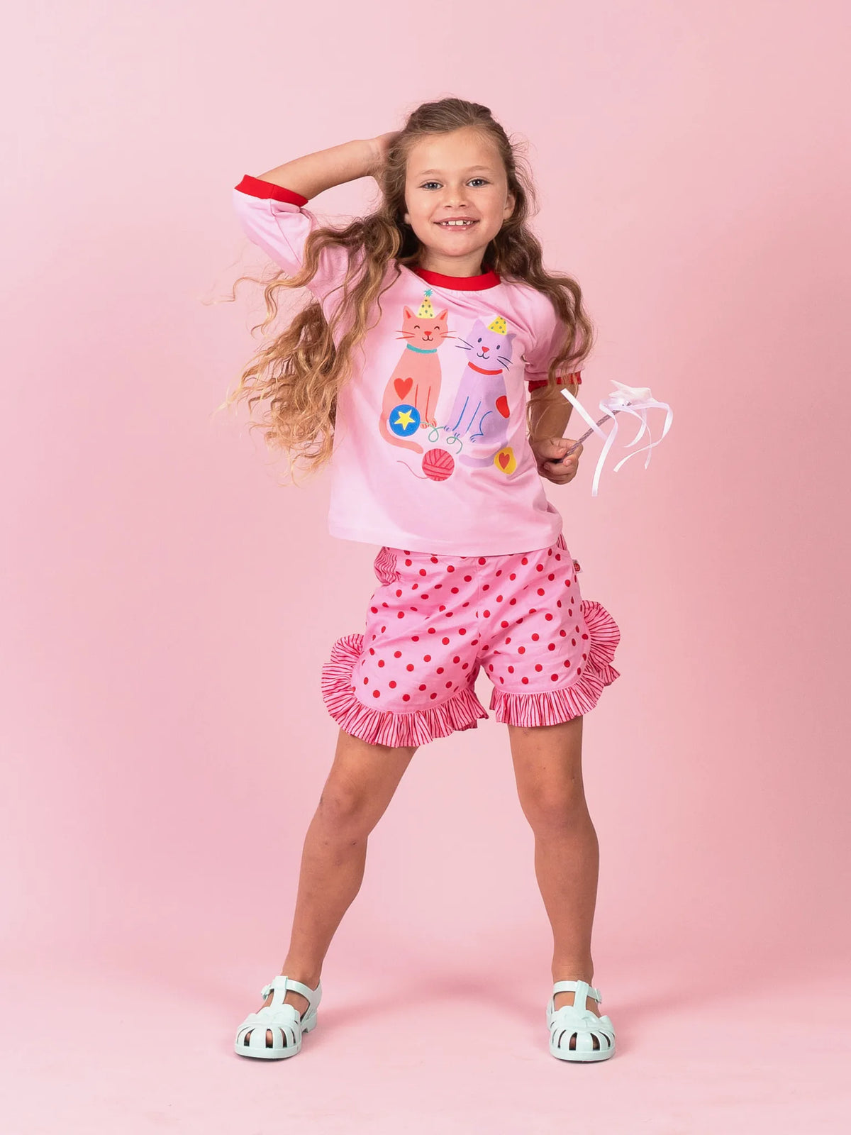 Girl dancing in Pink & Red Dots ruffle shorts and the Party Cats tee