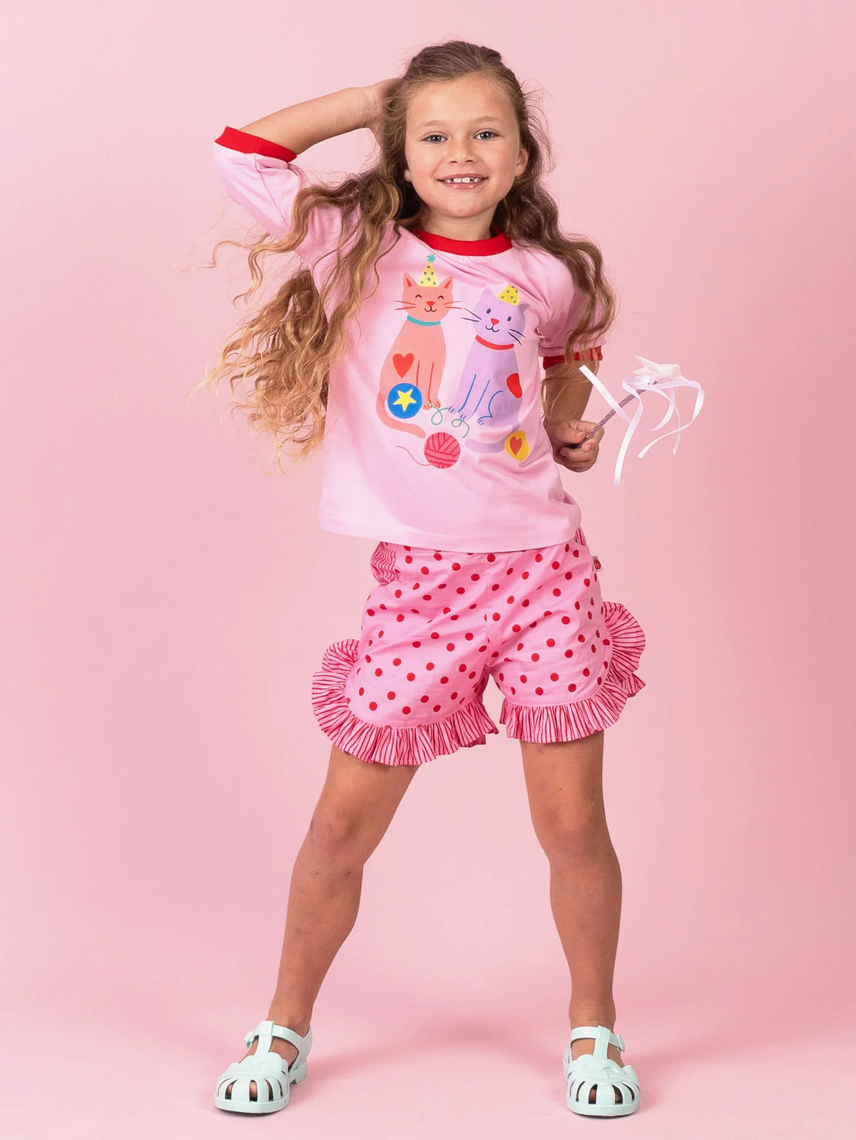Girl dancing in Pink & Red Dots ruffle shorts and the Party Cats tee