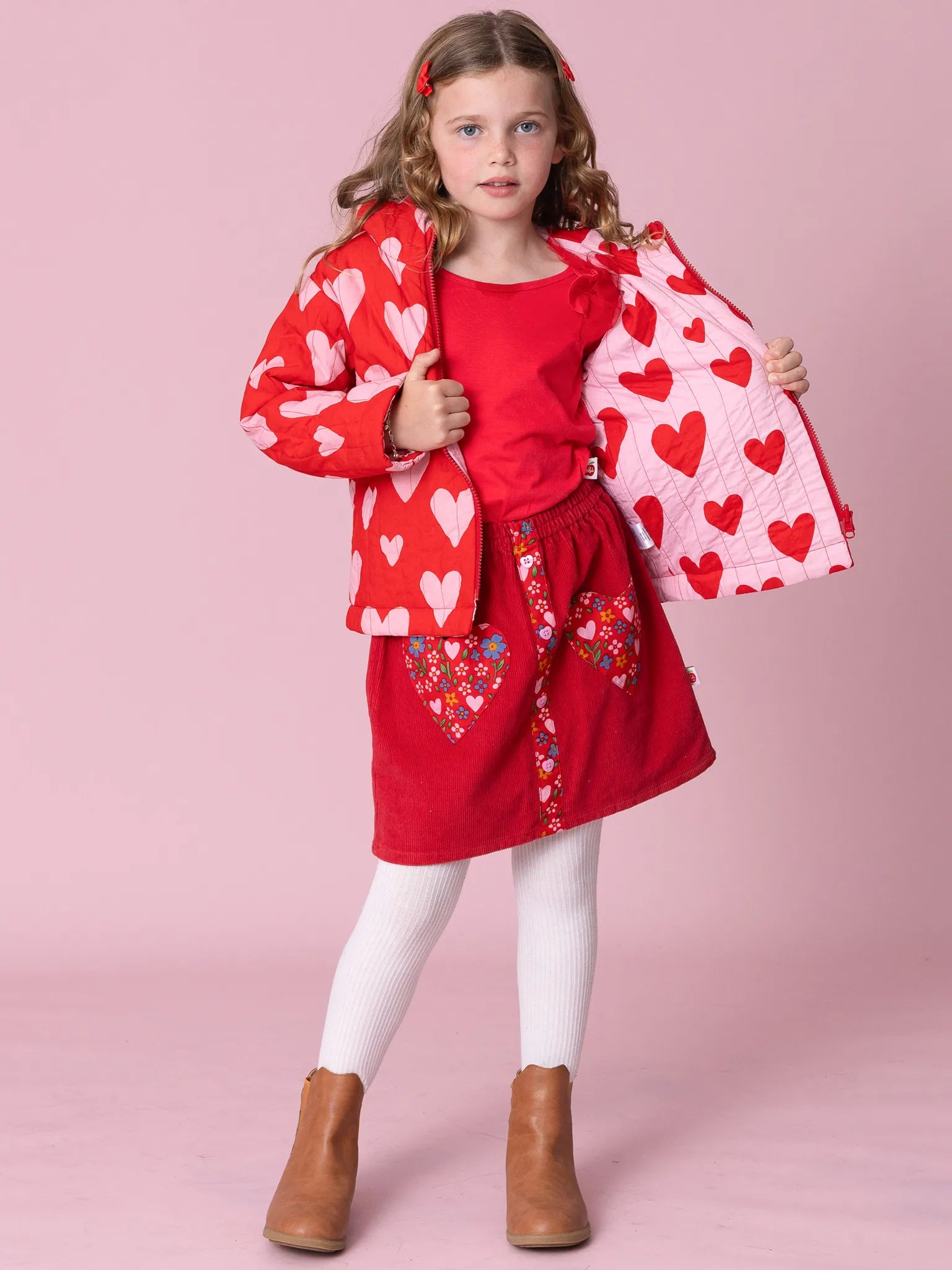 Young girl in a red outfit with heart patterns on a pink background