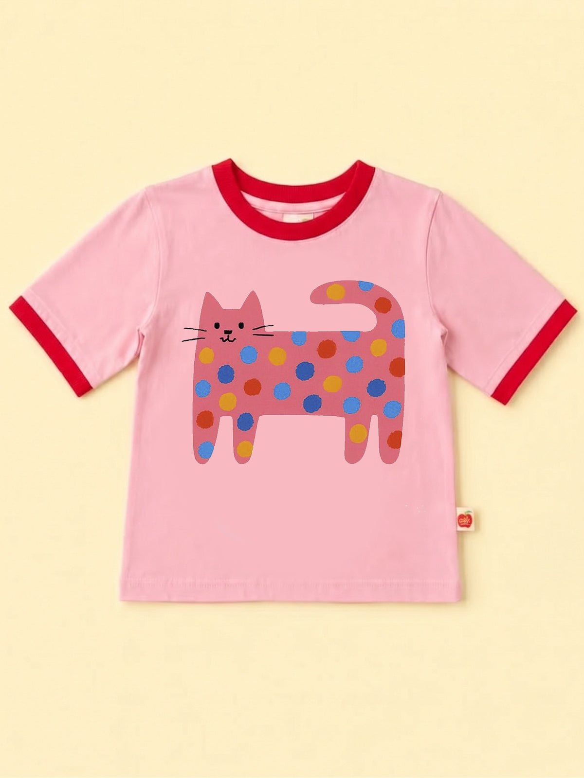 Pink Quirky Cat tee with red binding: a long cat covered in rainbow spots