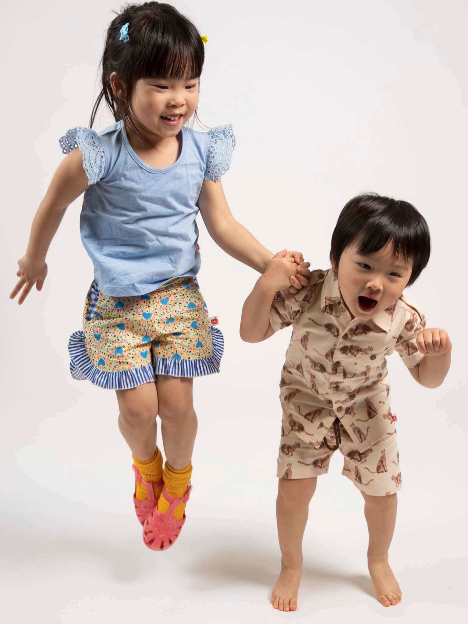 Two children in colorful outfits running on a white background