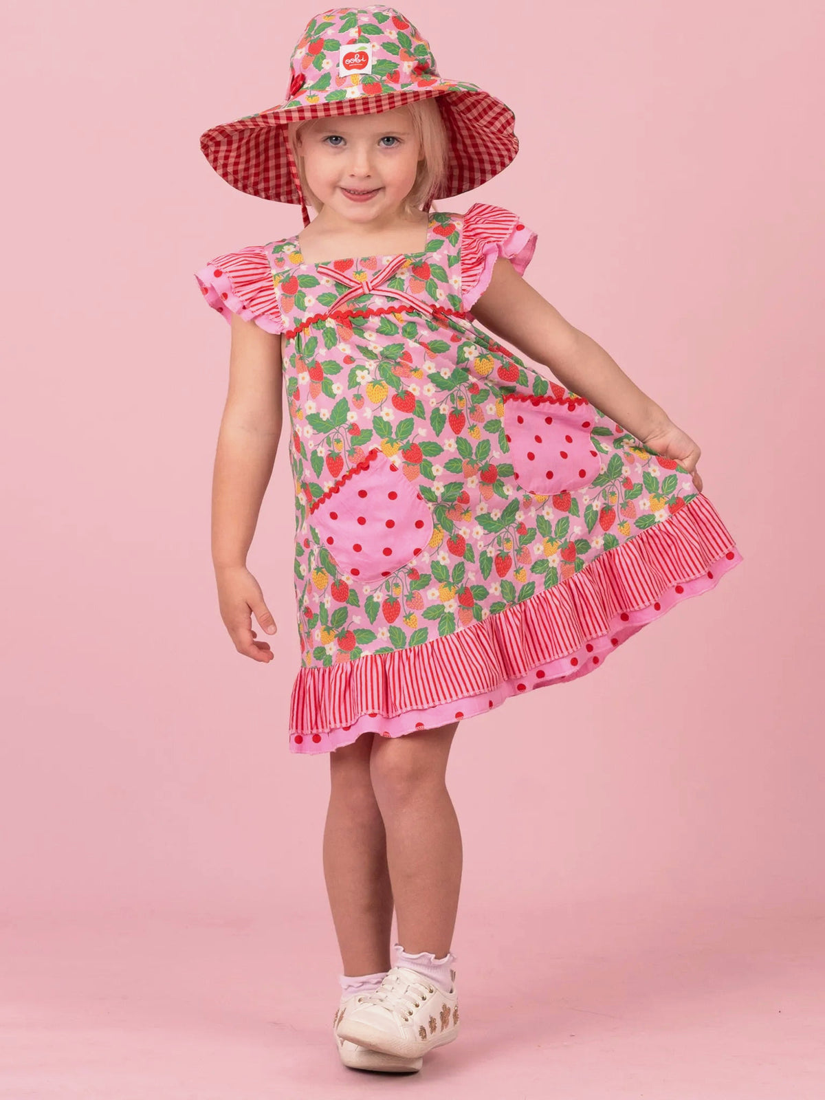 Girl in Strawberry Fields Holly dress with ruffled straps and pink gingham hem