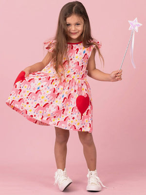 Girl twirling in Magical Unicorn skater dress with red heart pockets, holding a star wand