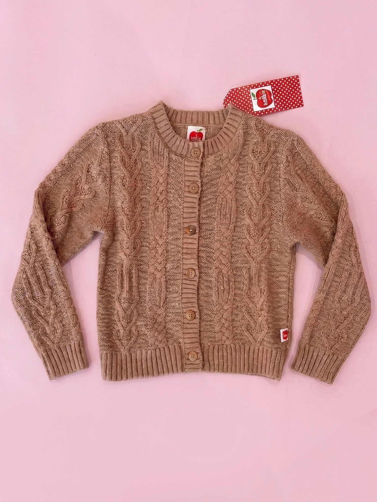 Brown cable knit cardigan on a pink background