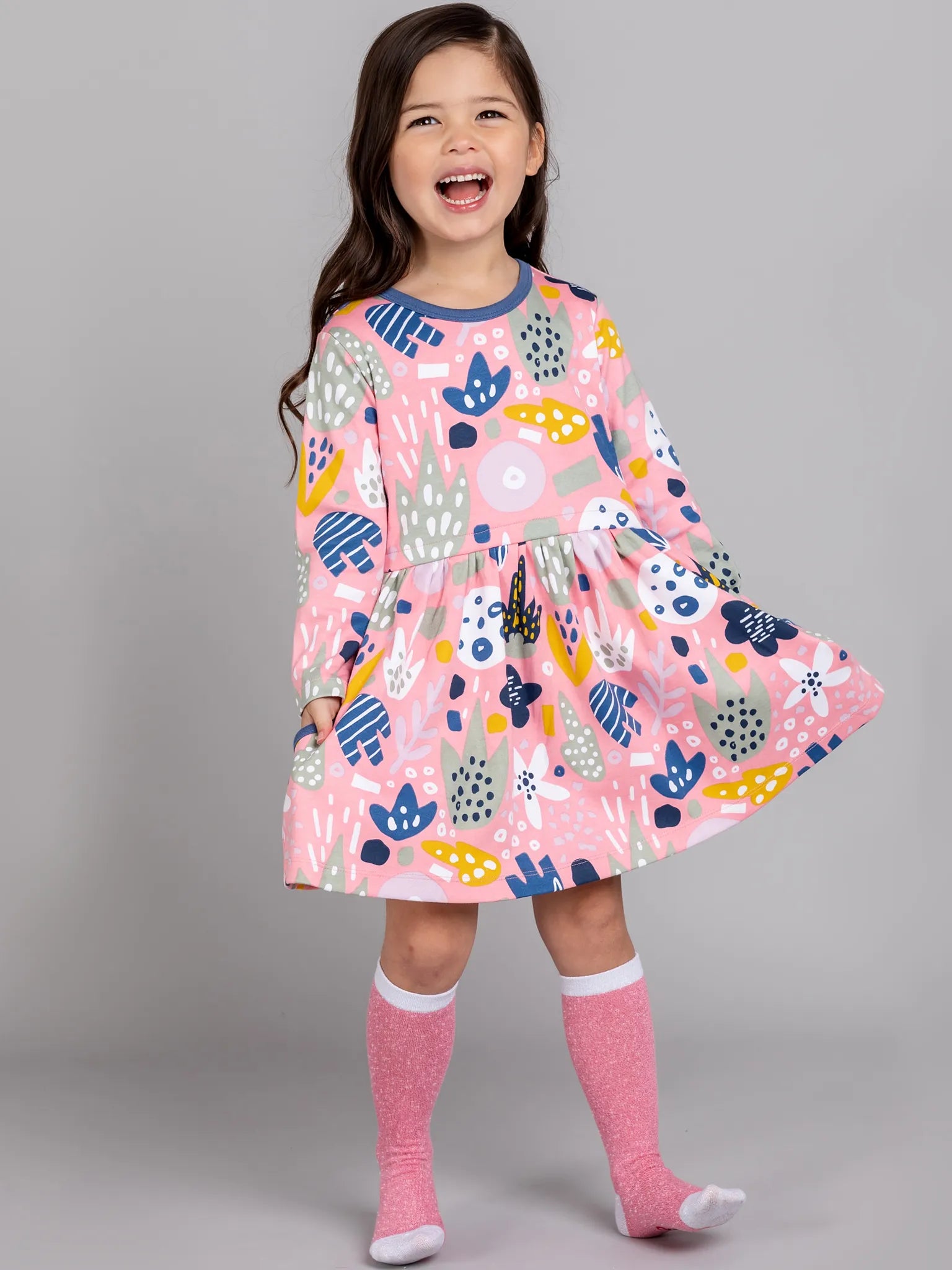 Child wearing a colorful dress with a pink background