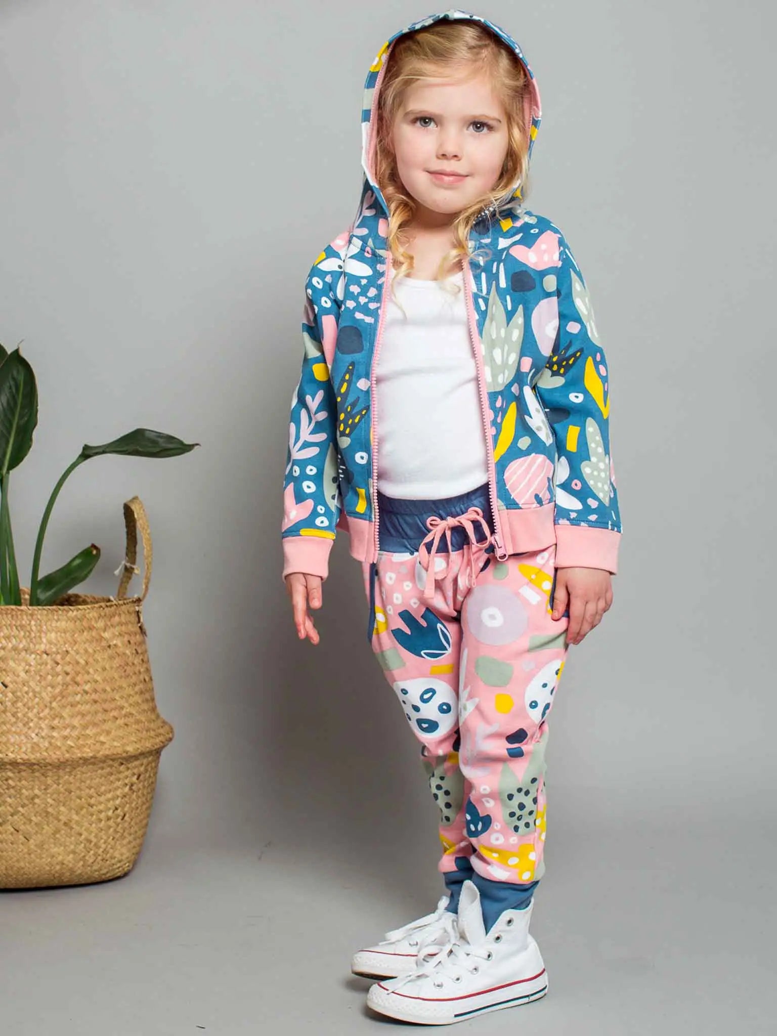 Child wearing a colorful outfit with a floral pattern against a plain background