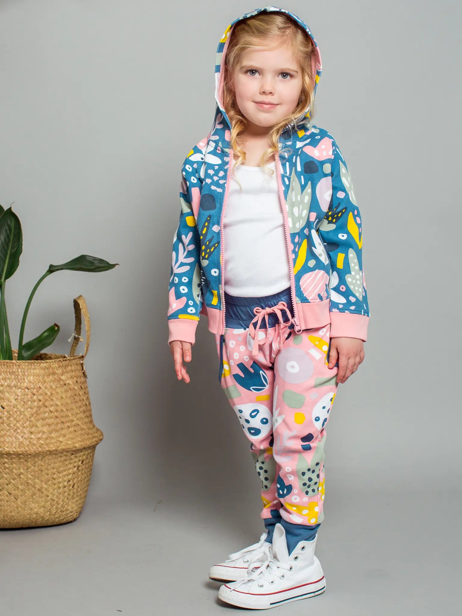 Child wearing a colorful outfit with a floral pattern on a gray background