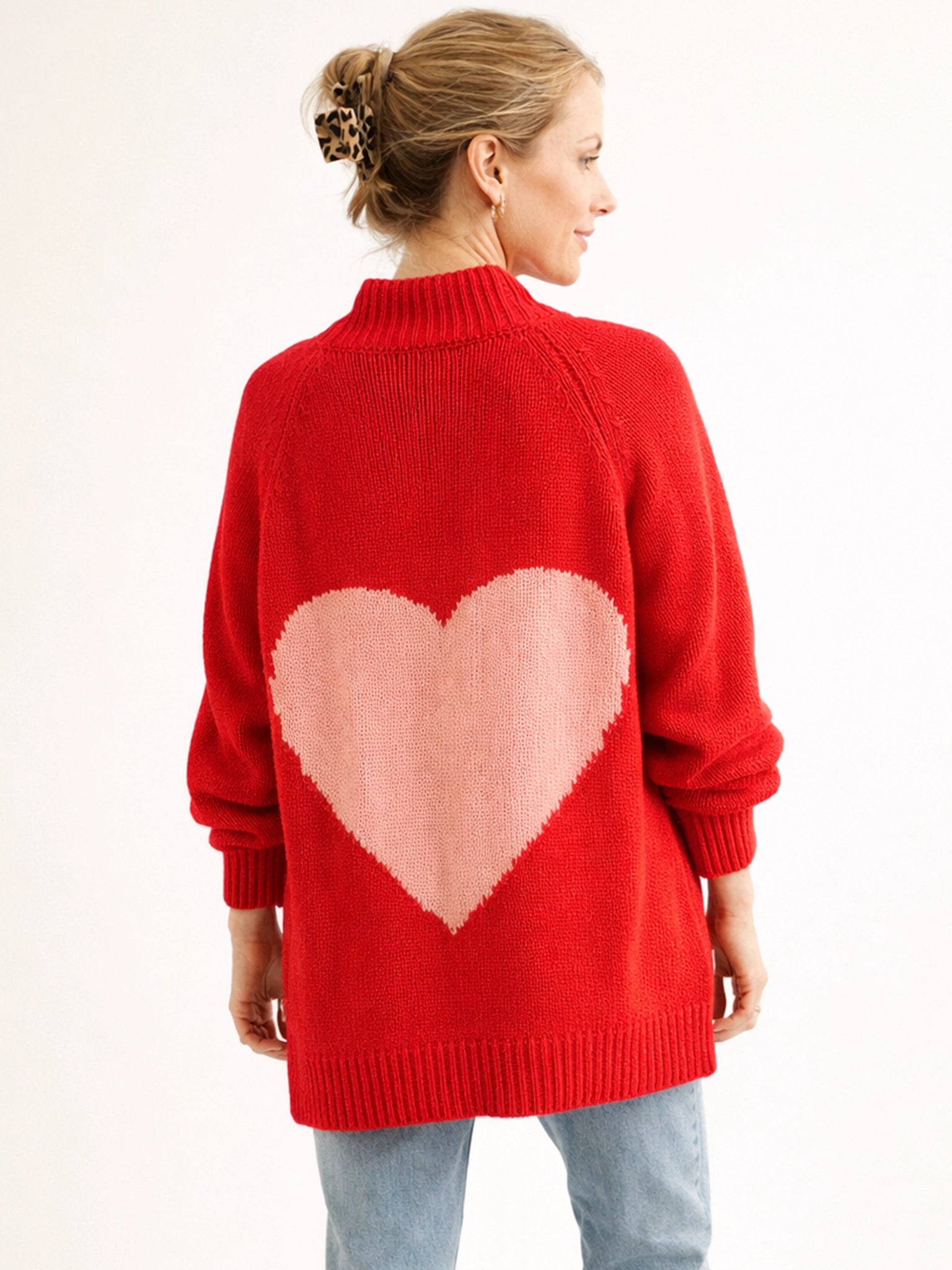 Red sweater with a pink heart design on the back, worn by a person.
