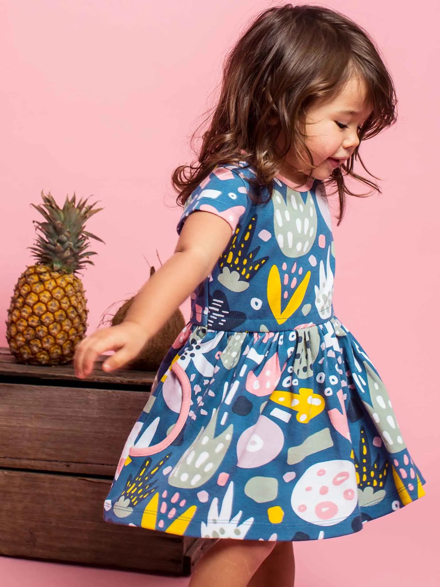 Smiling, twirling girl wearing a navy blue jungle print dress